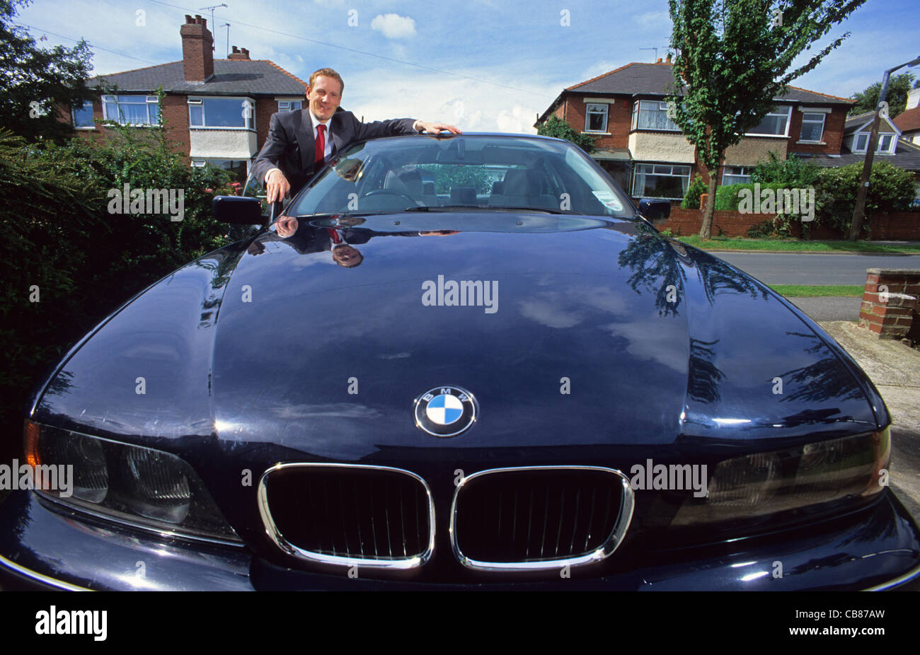 businessman leaning on bonnet of company car Stock Photo