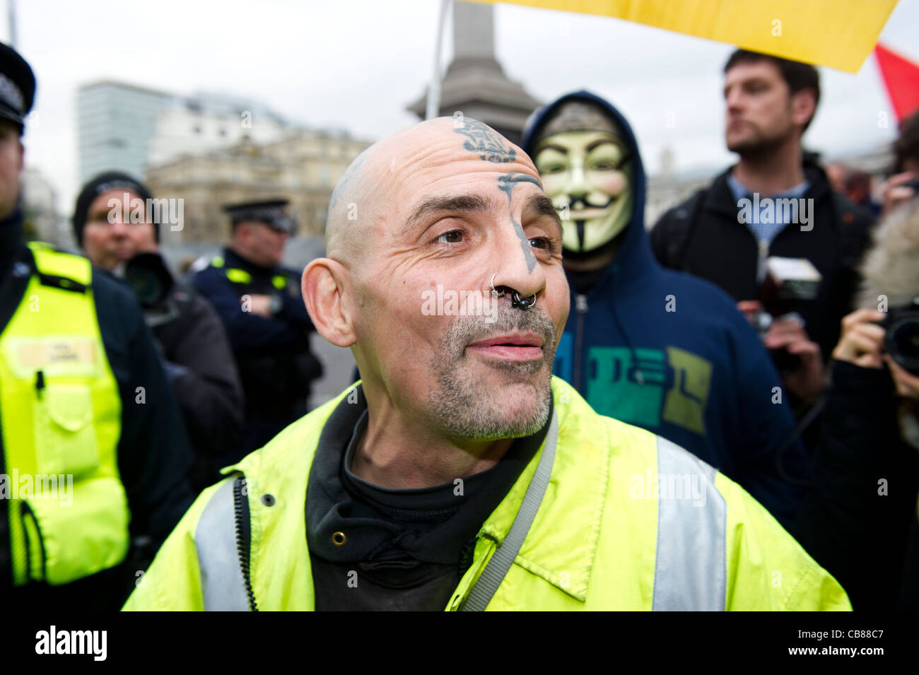 Bald headed tattooed man with piercings wearing reflective jacket having fun at public sector march in London. Stock Photo