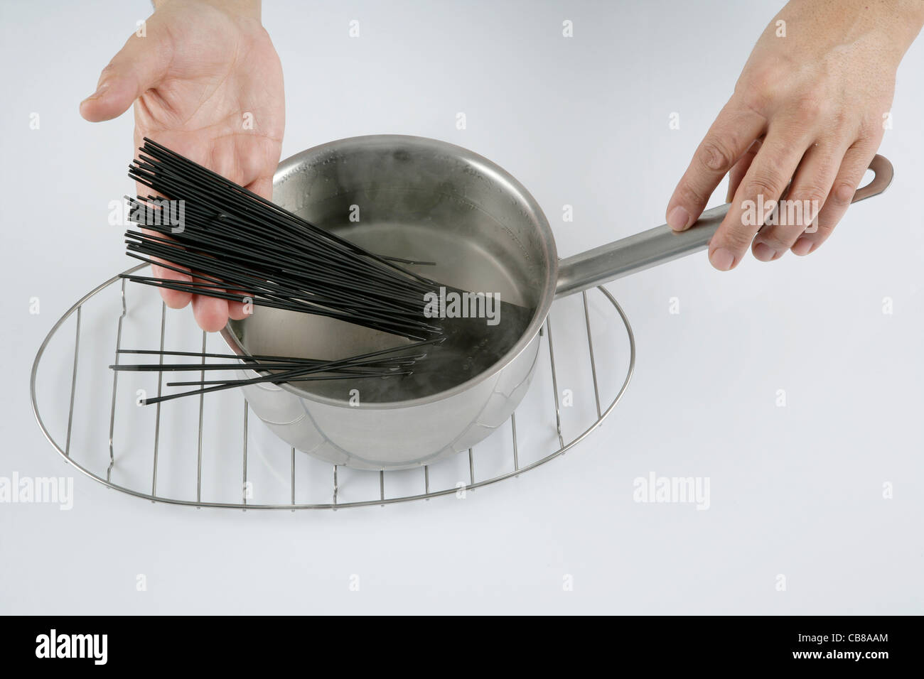 Putting black spaghetti into water to boil Stock Photo Alamy