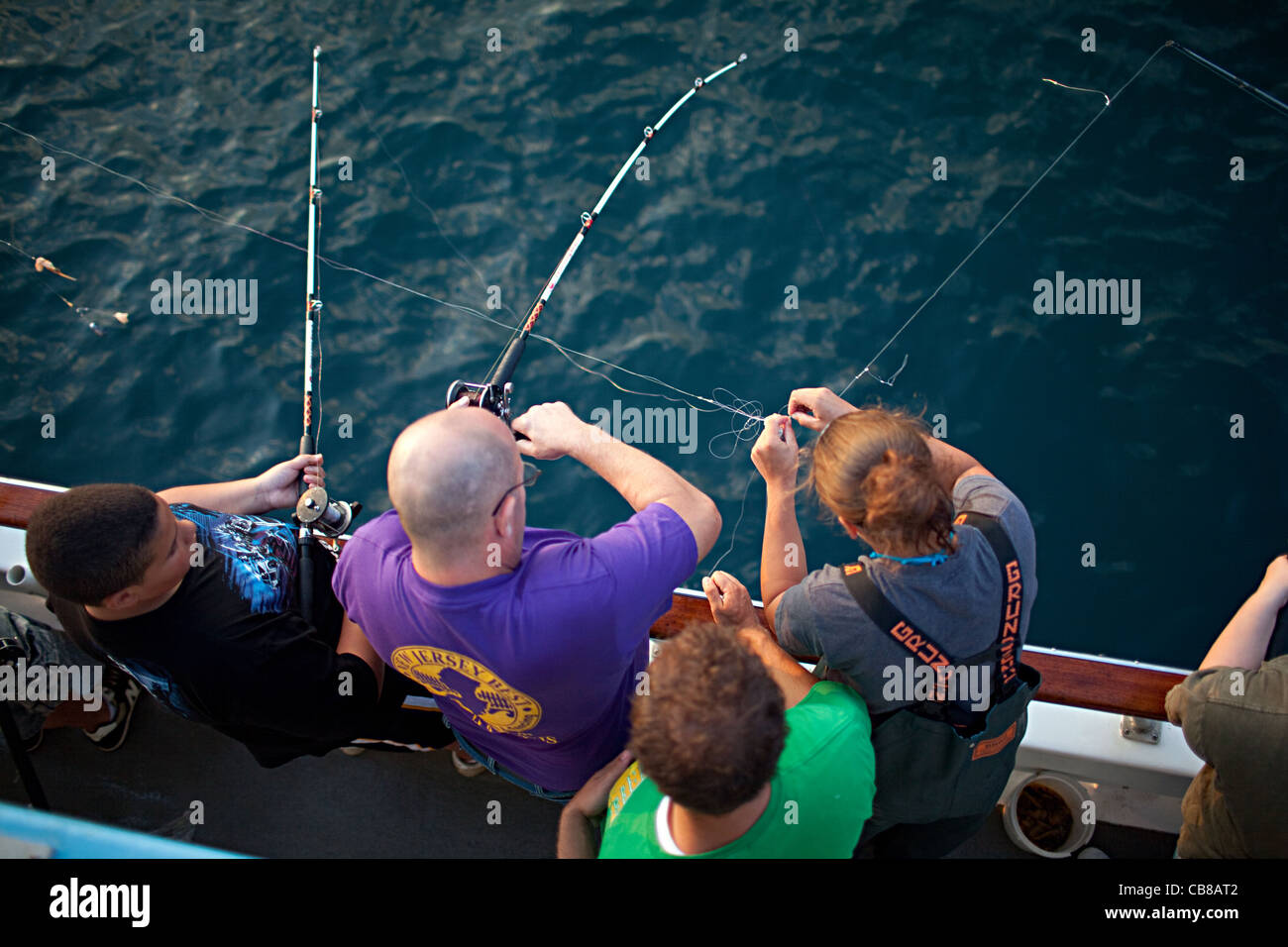 A deckhand, right, helps fishermen untangle their lines on a party boat off the coast of West