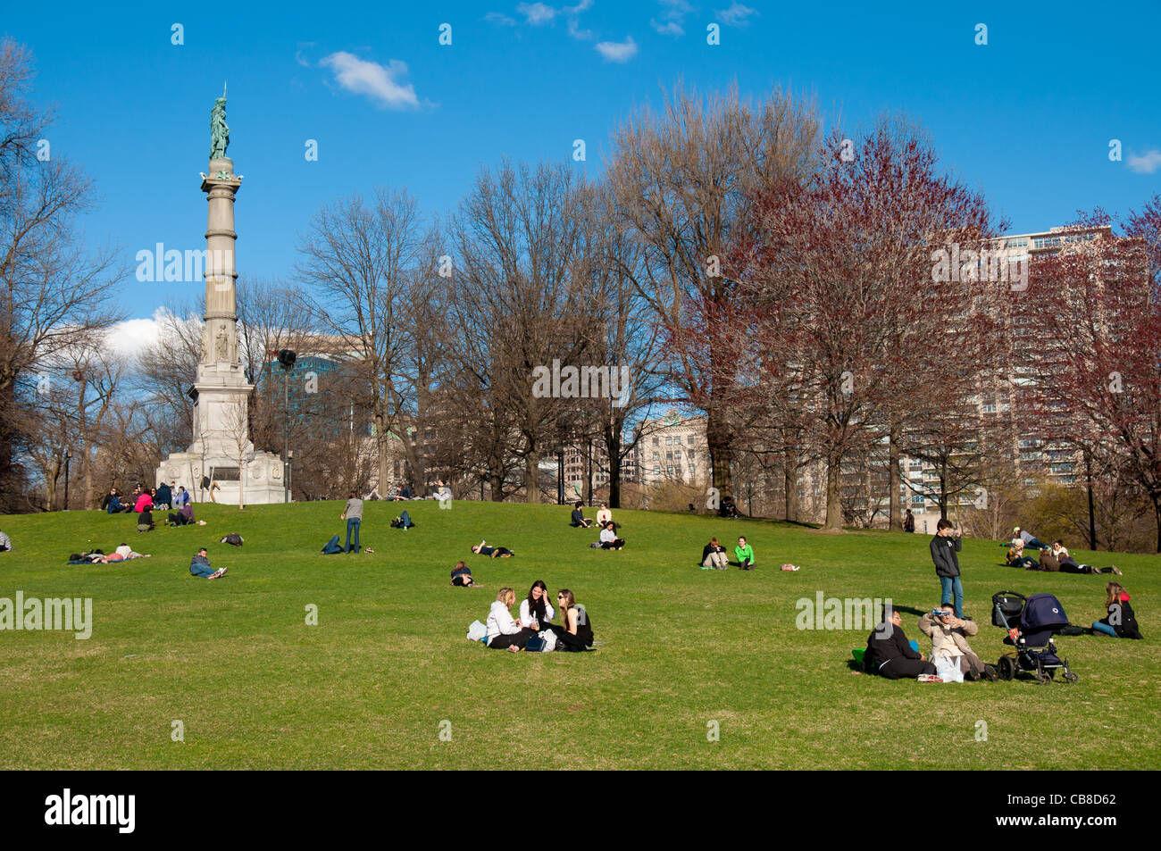 The Soldiers and Sailors Monument and people picnicking on the lawn in Boston Common park in spring Stock Photo