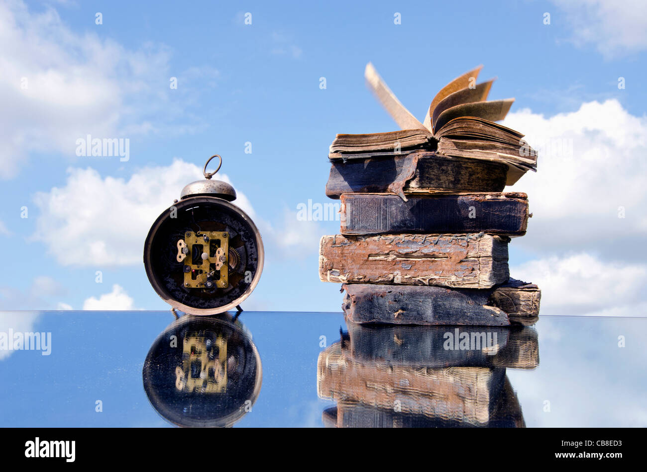 vintage books and old clock on mirror and sky Stock Photo
