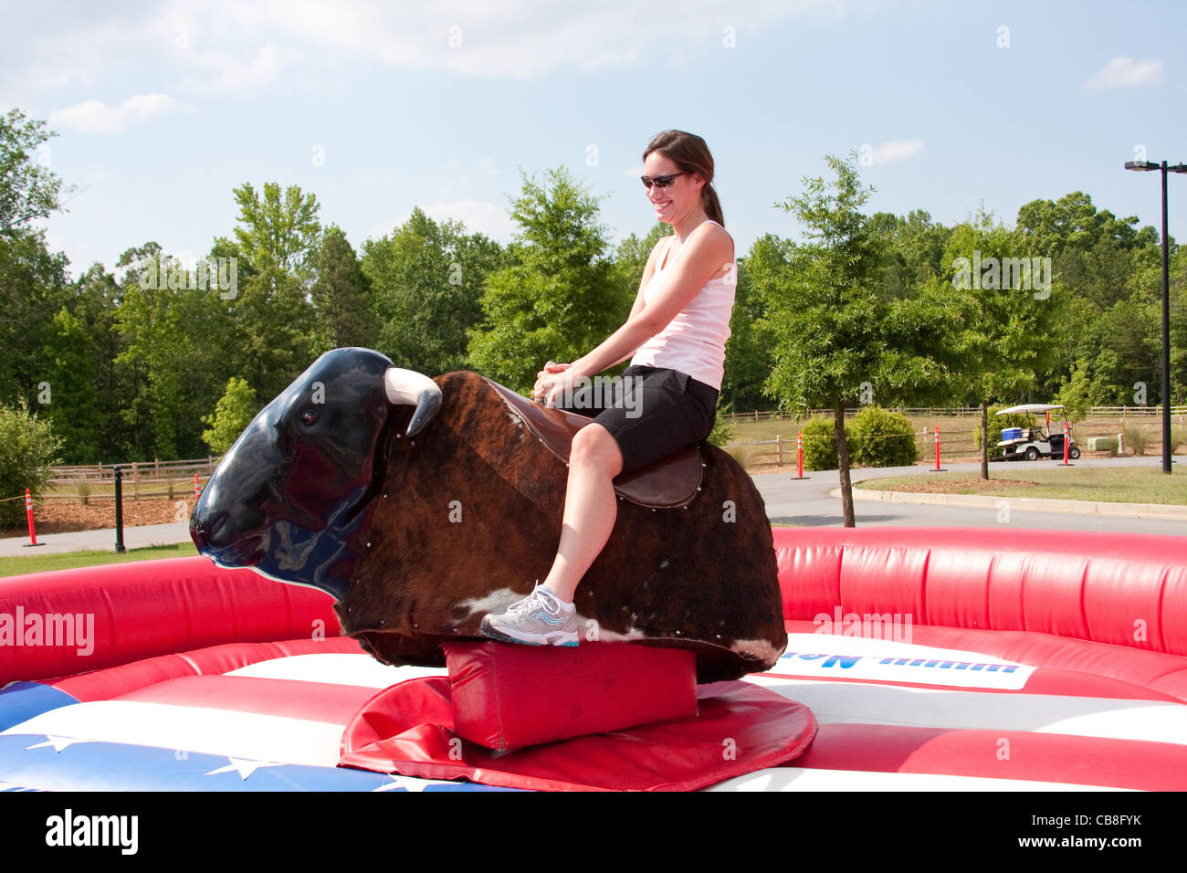 Woman riding a mechanical bull at a festival Stock Photo