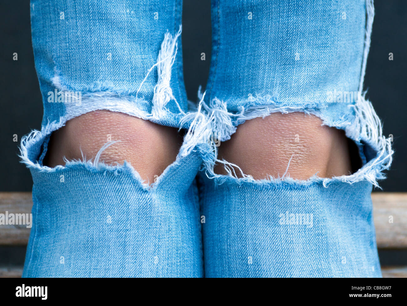 Closeup of teenager's knees in torn blue jeans. Stock Photo