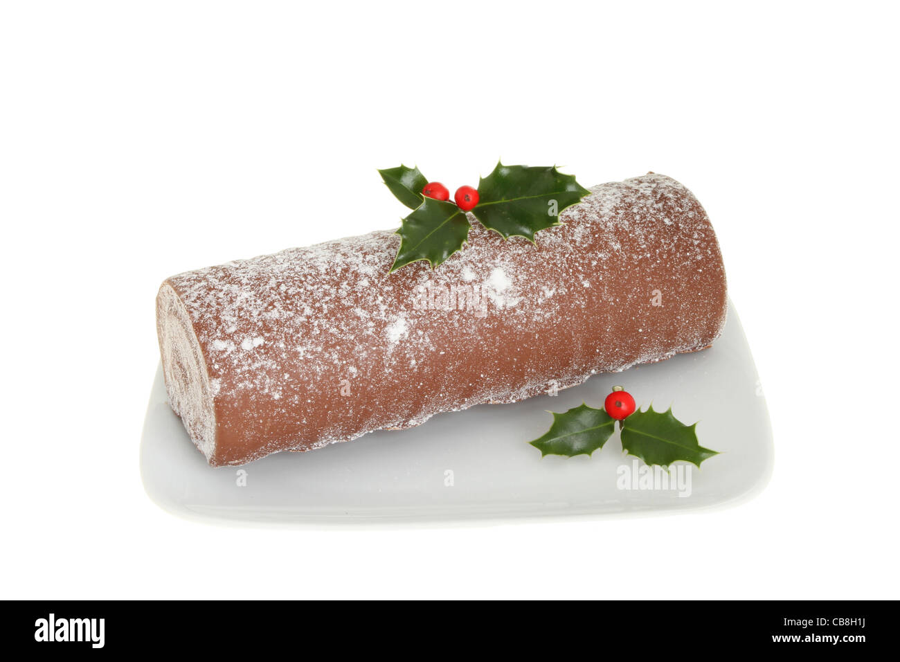 Christmas chocolate log decorated with holly on a plate isolated against white Stock Photo