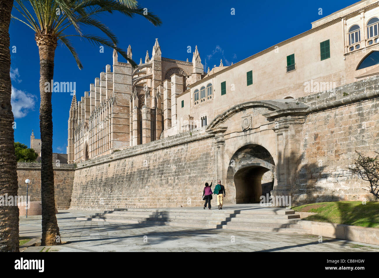 Palma Cathedral and historic Parc de la Mar with tourist couple standing looking at old stone entrance Mallorca Balearics Spain Stock Photo