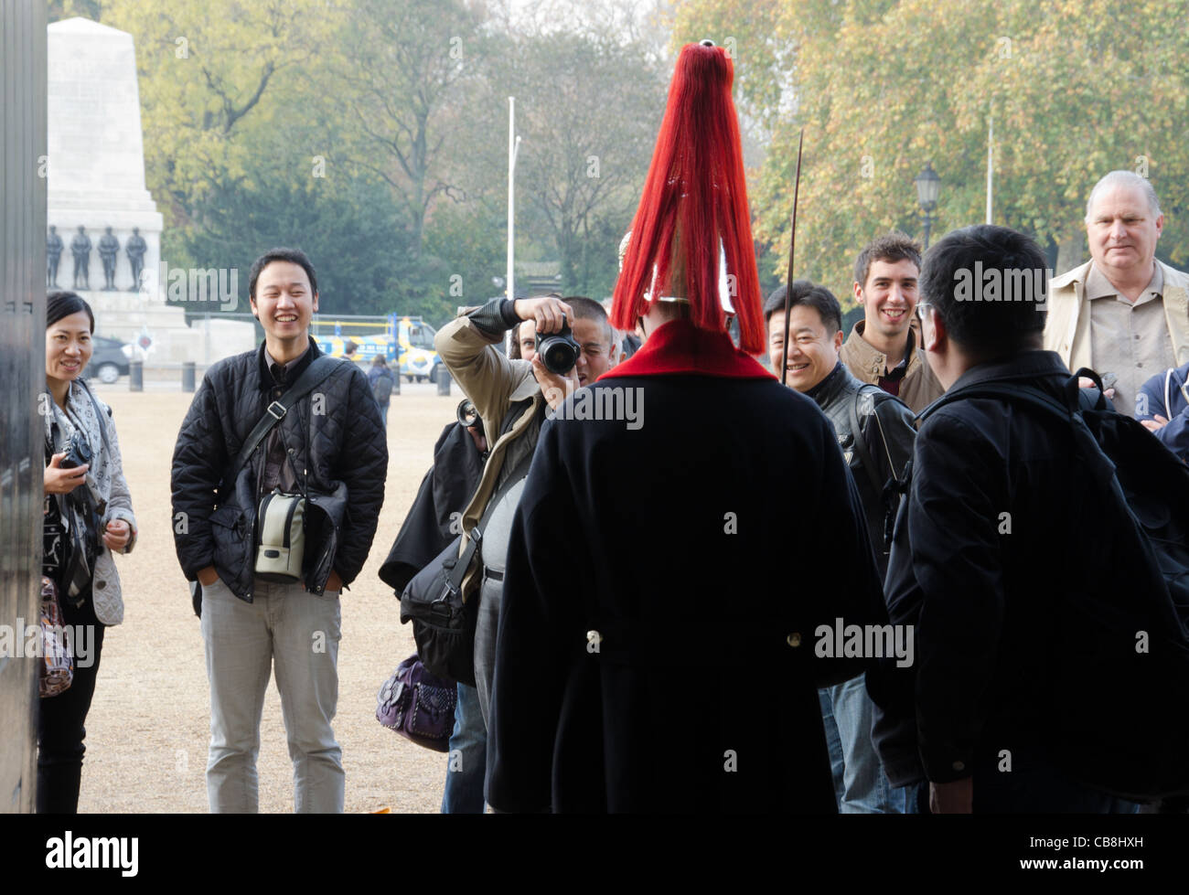 Foreign tourists posing for pictures with unmounted trooper of the British Household Cavalry in Horse Guards Parade, London Stock Photo