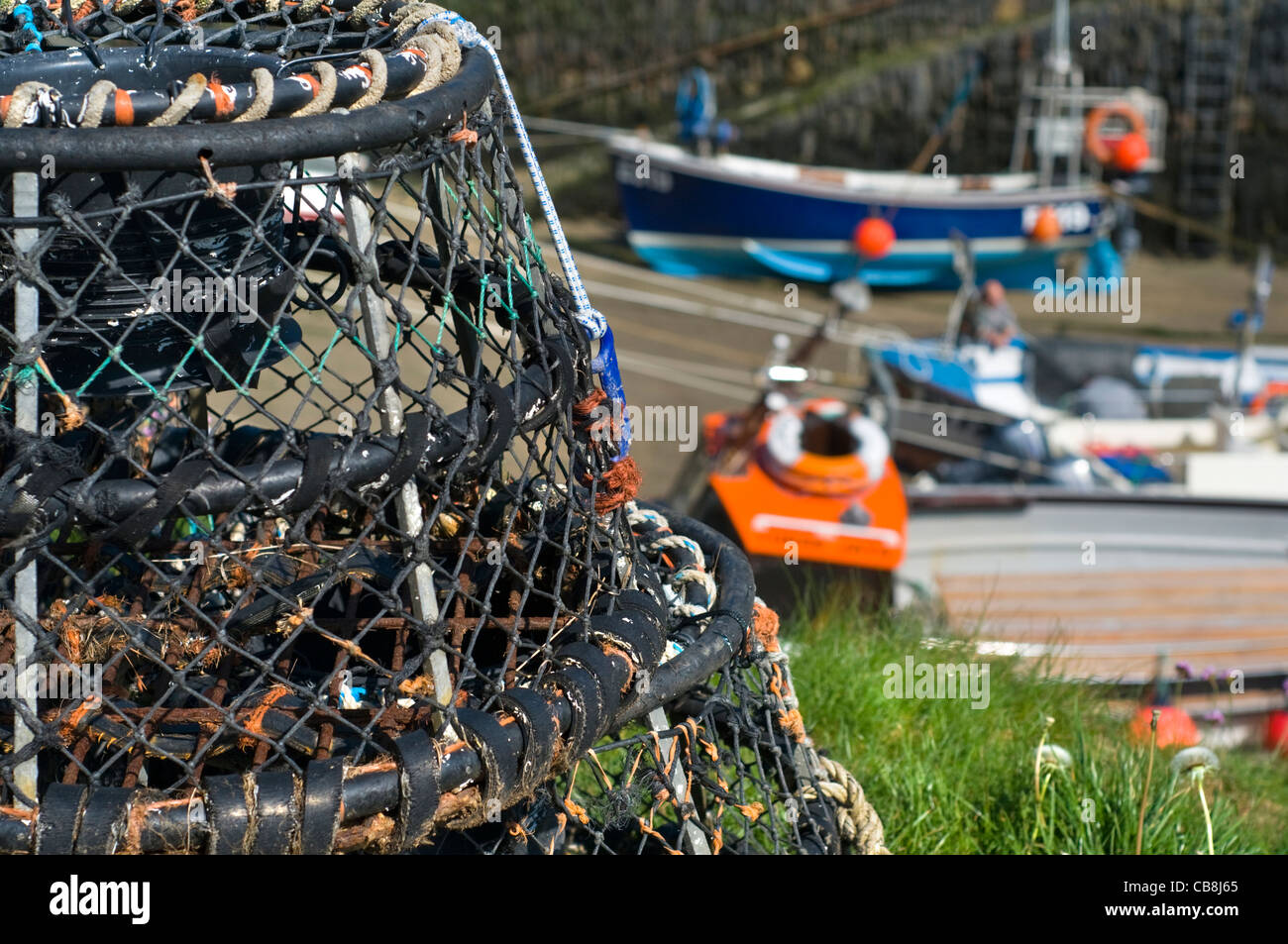 Lobster pots in the harbour at Boscastle in Cornwall, England, with fishing boats in the background Stock Photo