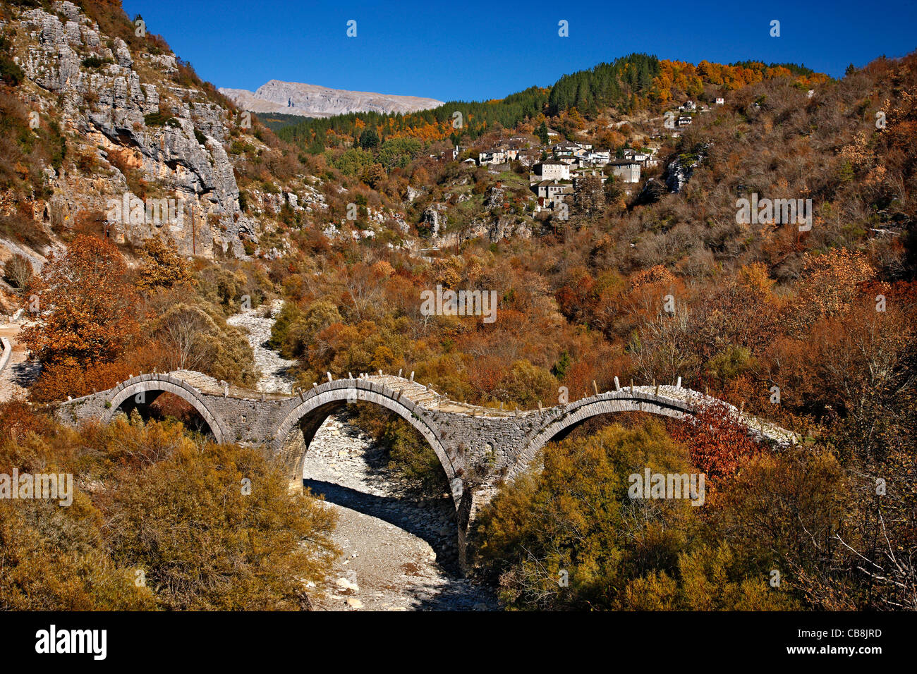 The 3- arched stone bridge known as 'Kalogeriko' or 'Plakidas' bridge, Zagori region, Ioannina, Greece. In the BG, Kipoi village Stock Photo