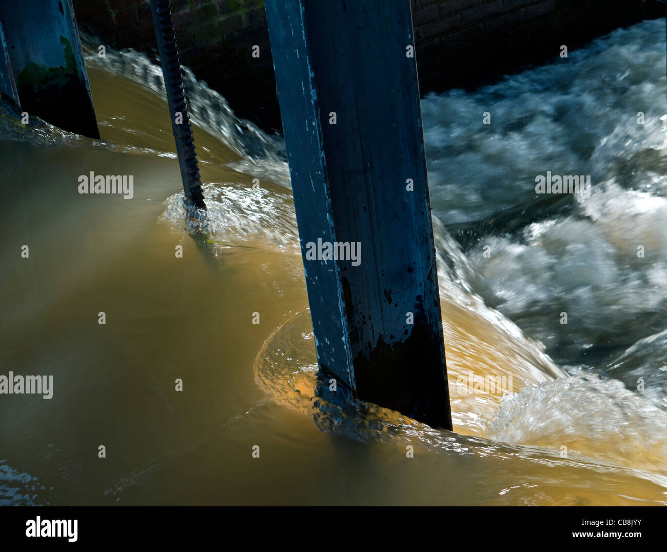 WATER FLOWING WEIR River in flood after recent heavy rainfall with brackish water flowing over a weir Stock Photo