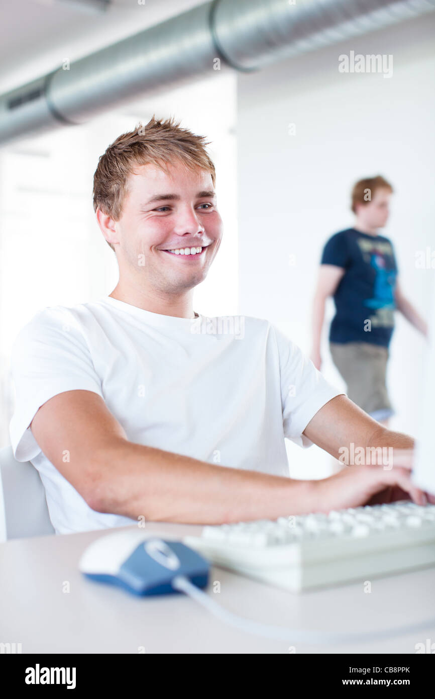 handsome college student using a computer in a college/university ...