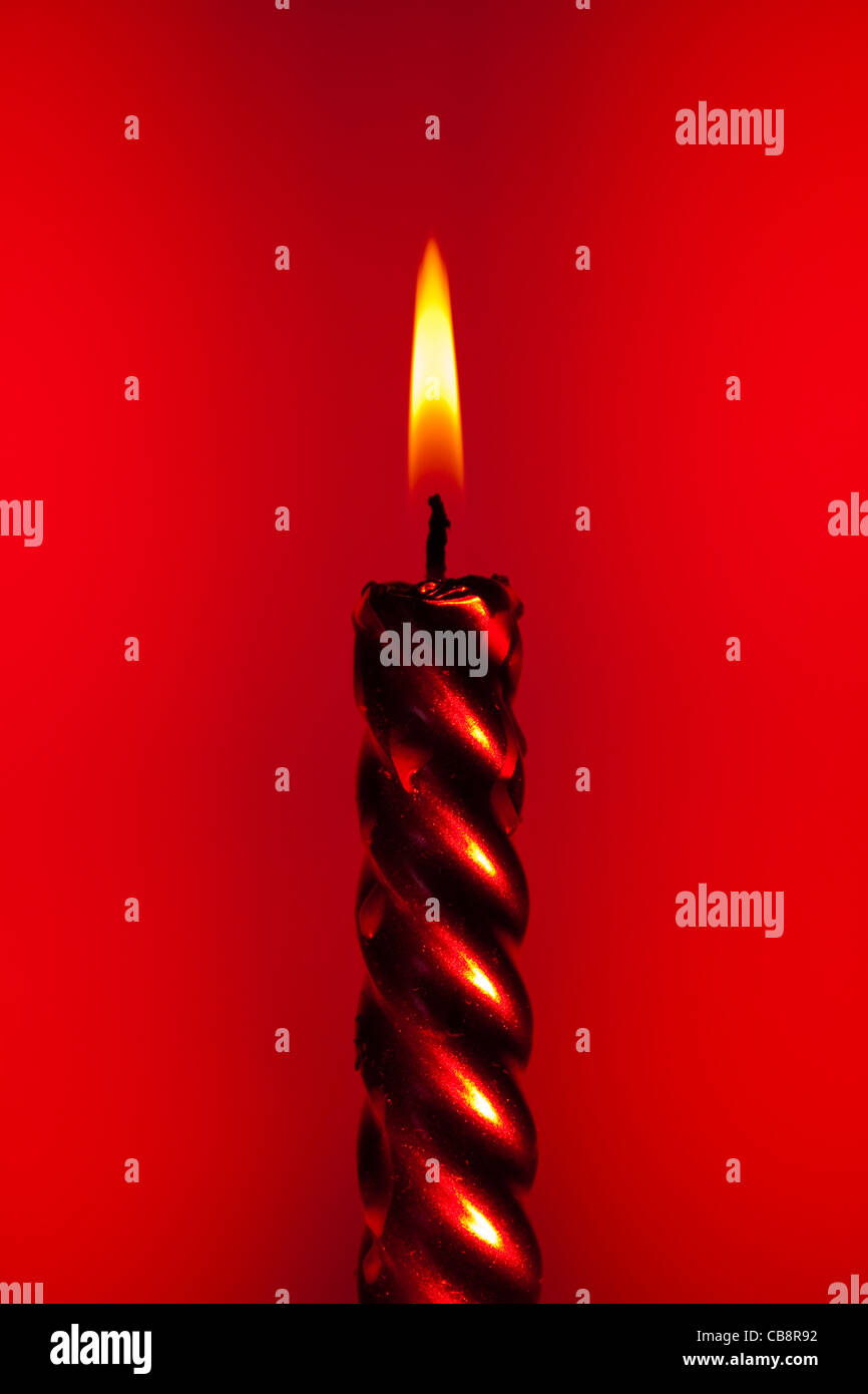 red burning candle on colourful vivid background Stock Photo