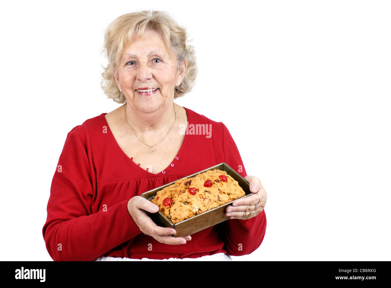 Mother and grand-mother welcoming her family with a smile and a freshly baked home made fruit cake. Stock Photo