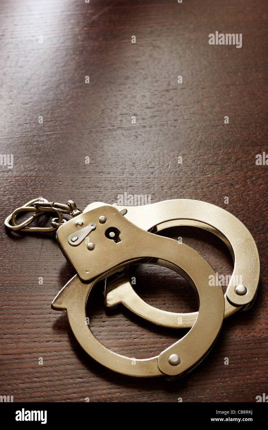 handcuffs on the wooden desk, crime concept Stock Photo