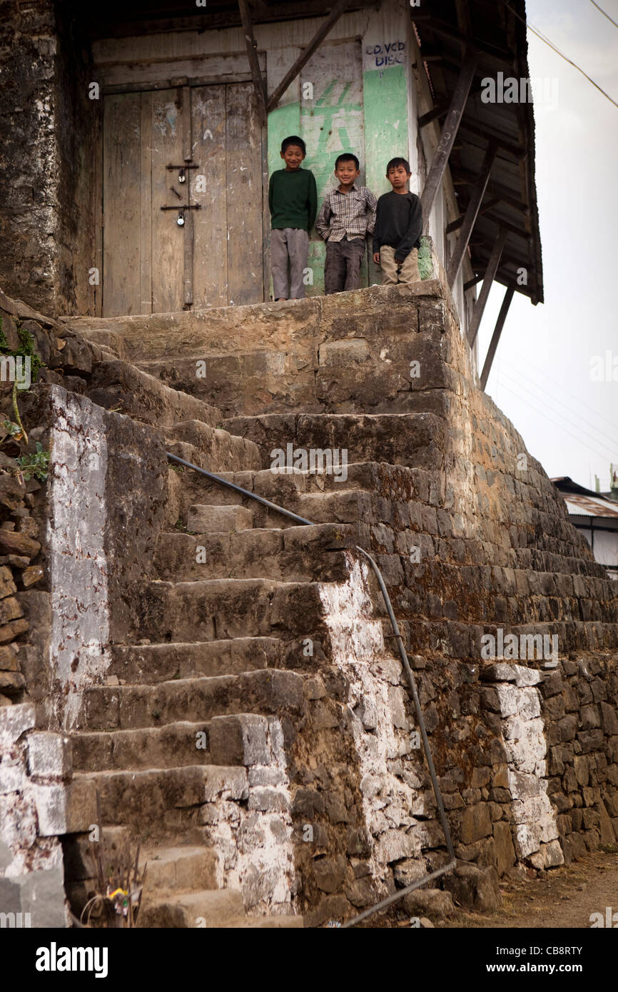 India, Nagaland, Jakhama Village, three young children looking down from house Stock Photo