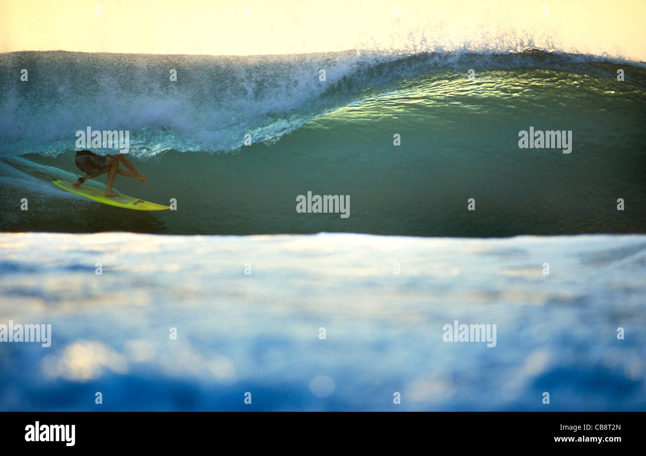 Surfing deep in the tube on a sunset emerald wave. Desert Point, Lombok, Indonesia, Southeast Asia, Asia Stock Photo