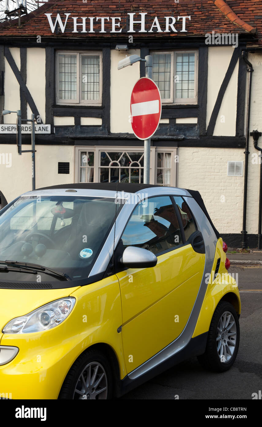 Yellow Smart Fortwo car parked by a No Entry sign outside the White Hart pub old town Beaconsfield Bucks UK Stock Photo