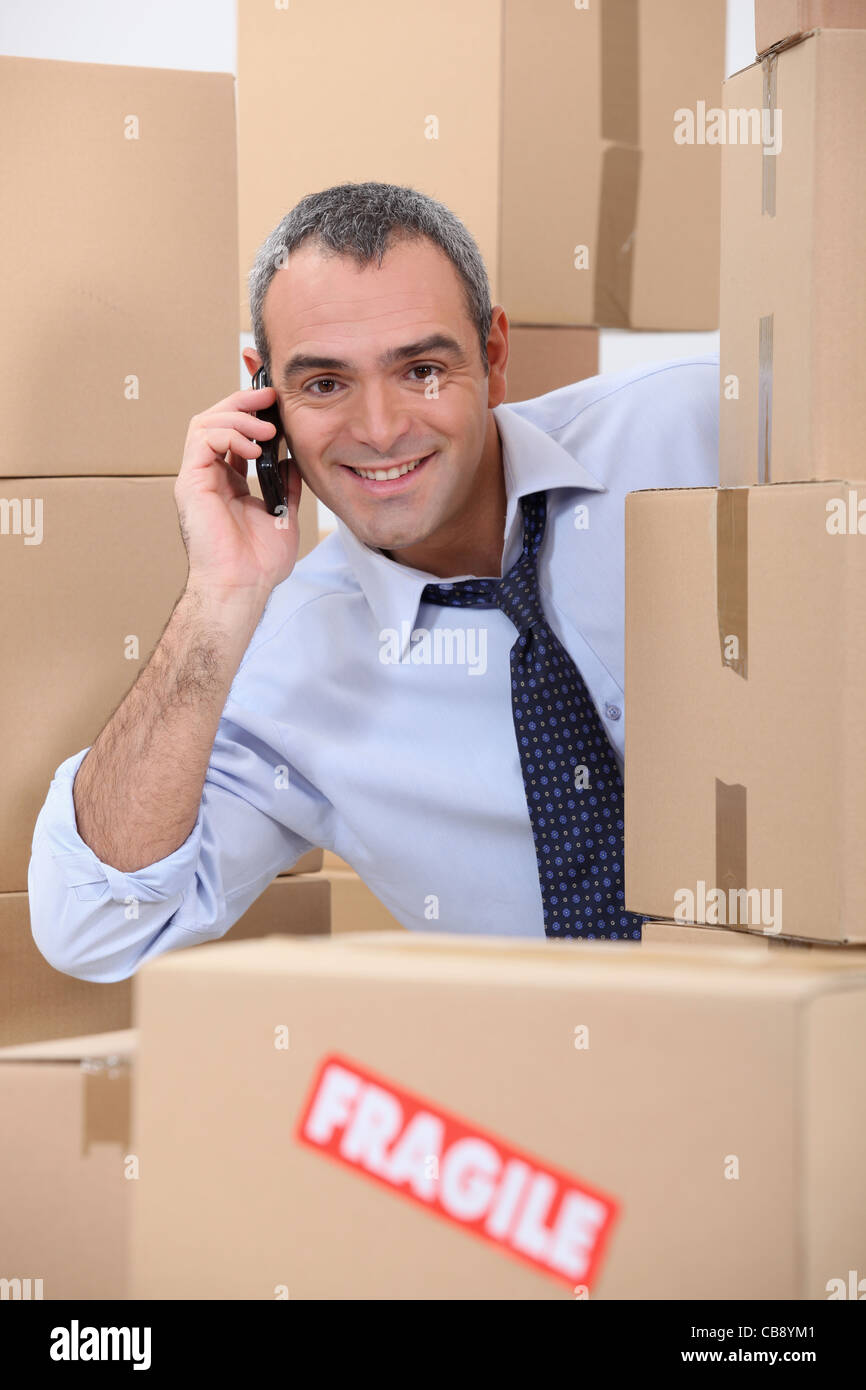 a 4045 years old employee calling someone in a room full of cardboard