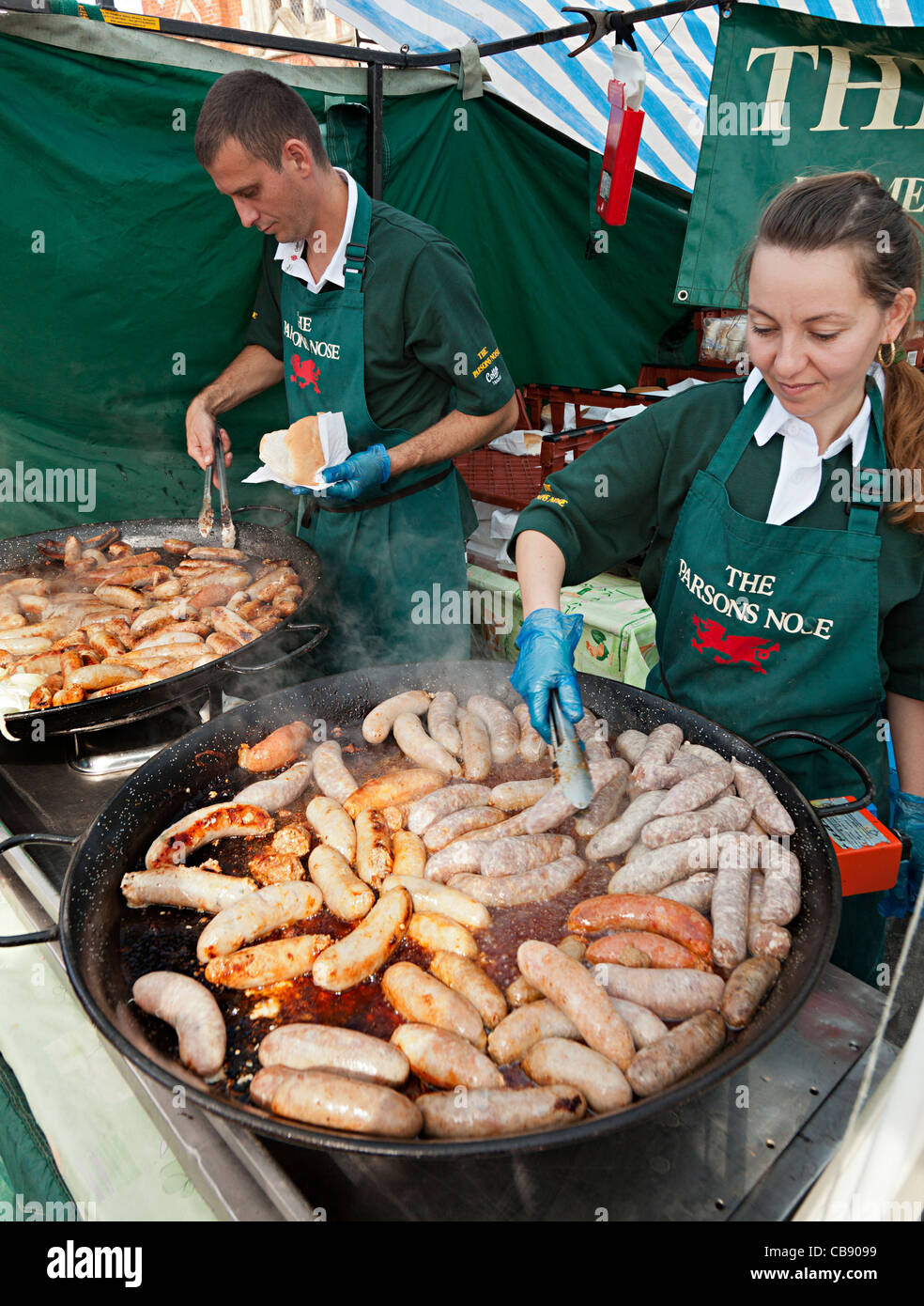Man and woman cooking sausages at Abergavenny Food Festival Wales UK Stock Photo