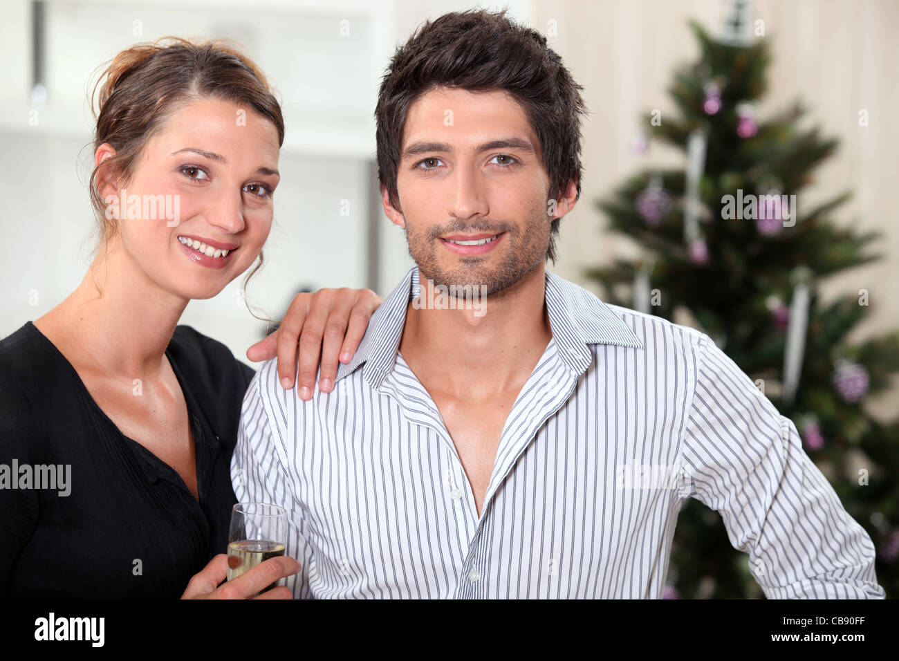 a couple behind a Christmas tree inside an apartment Stock Photo