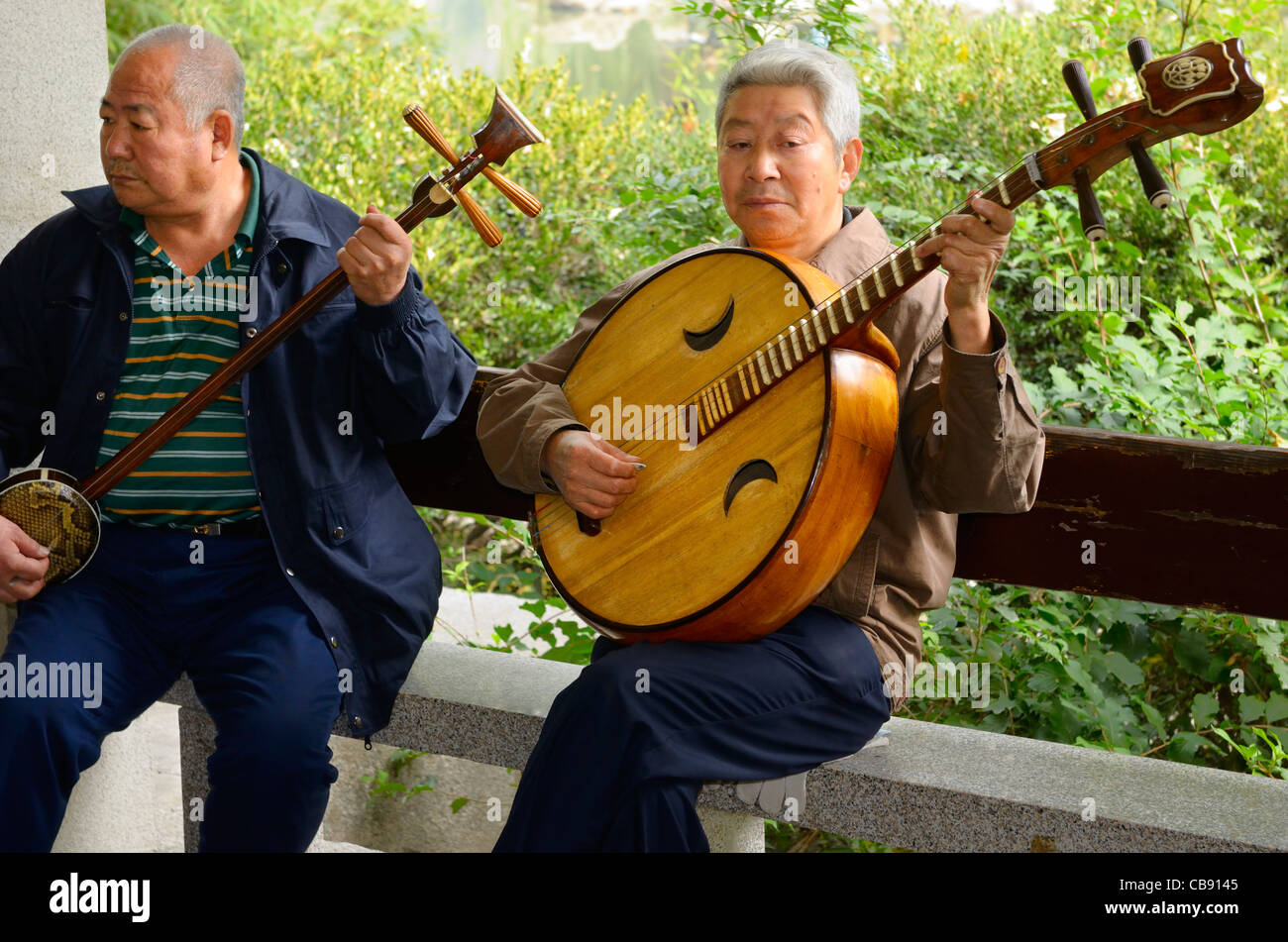 Two men playing a Chinese banjo and Ruan in an orchestra outdoors at Zizhuyuan Purple Bamboo Park in Beijing Peoples Republic of China Stock Photo