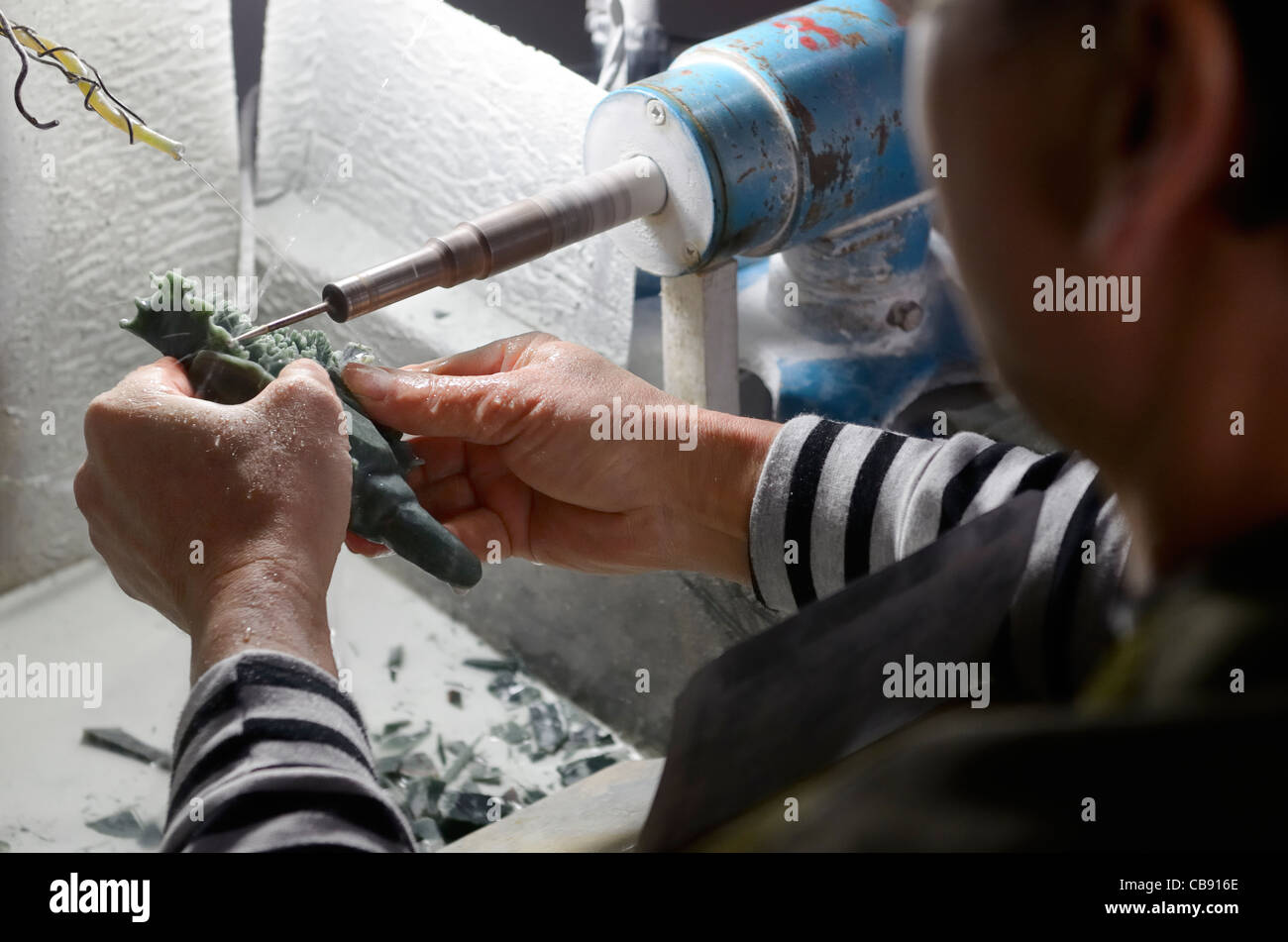 Craftsman carving jade stone with a water cooled diamond dremel drill in Beijing Peoples Republic of China Stock Photo