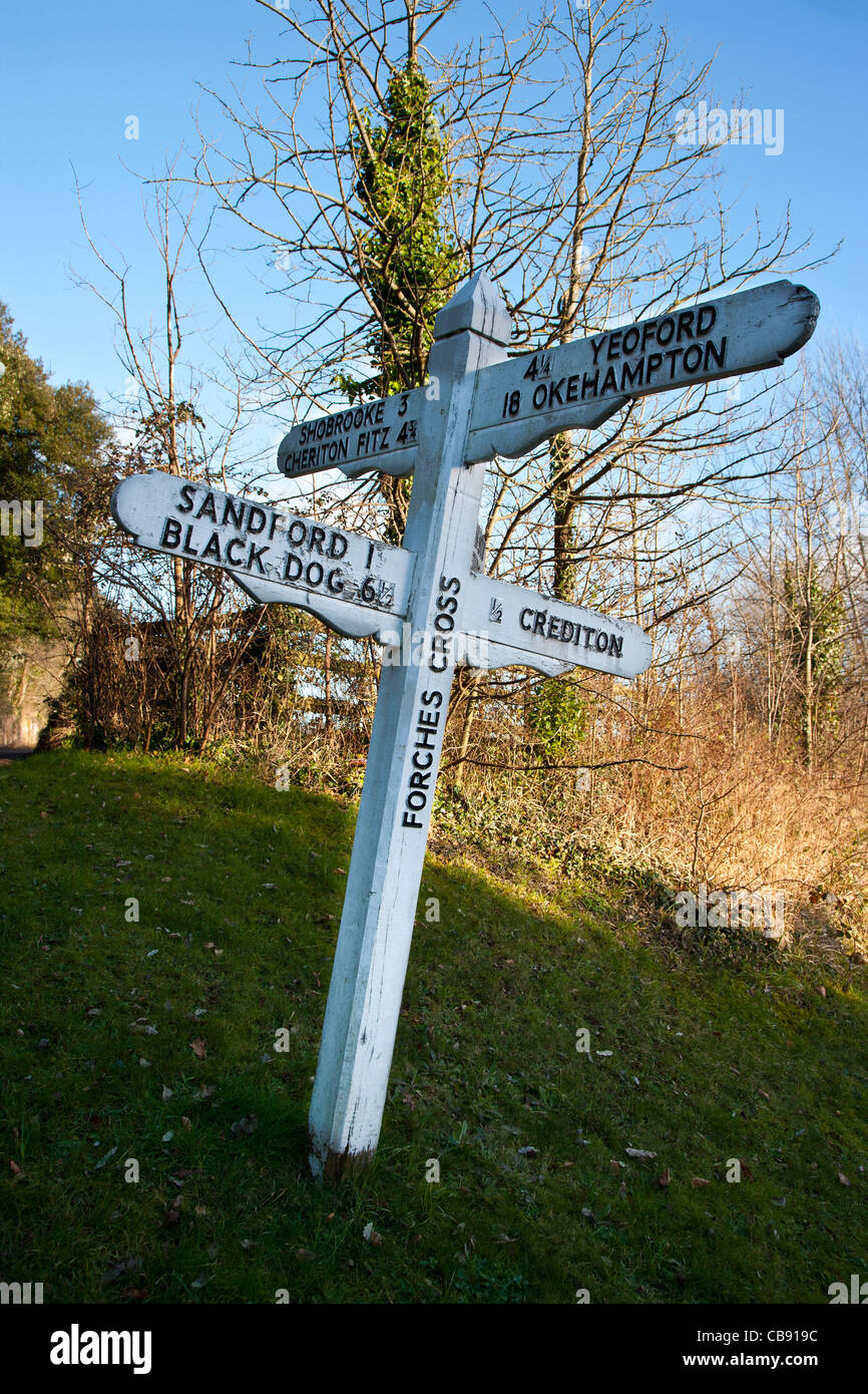Old direction sign in white and black near Crediton, Devon, England, showing way to a hamlet called Black Dog Stock Photo
