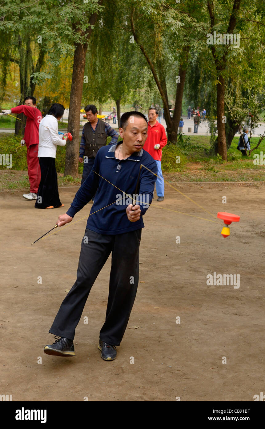 Man spinning a Chinese Yo Yo in Zizhuyuan Purple Bamboo Park in Beijing Peoples Republic of China Stock Photo