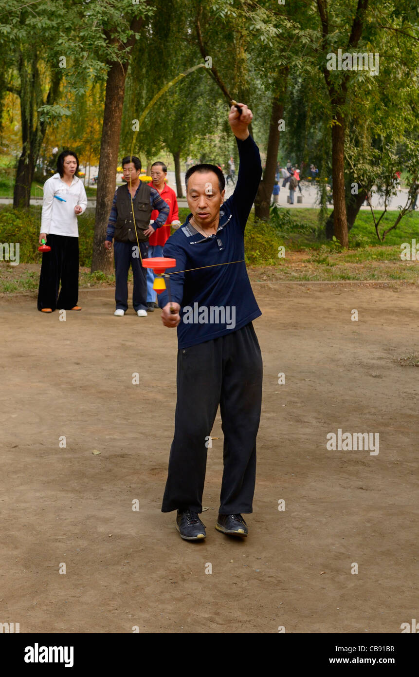 Skilled man doing tricks with Chinese Yo Yo in Zizhuyuan Purple Bamboo Park in Beijing Peoples Republic of China Stock Photo