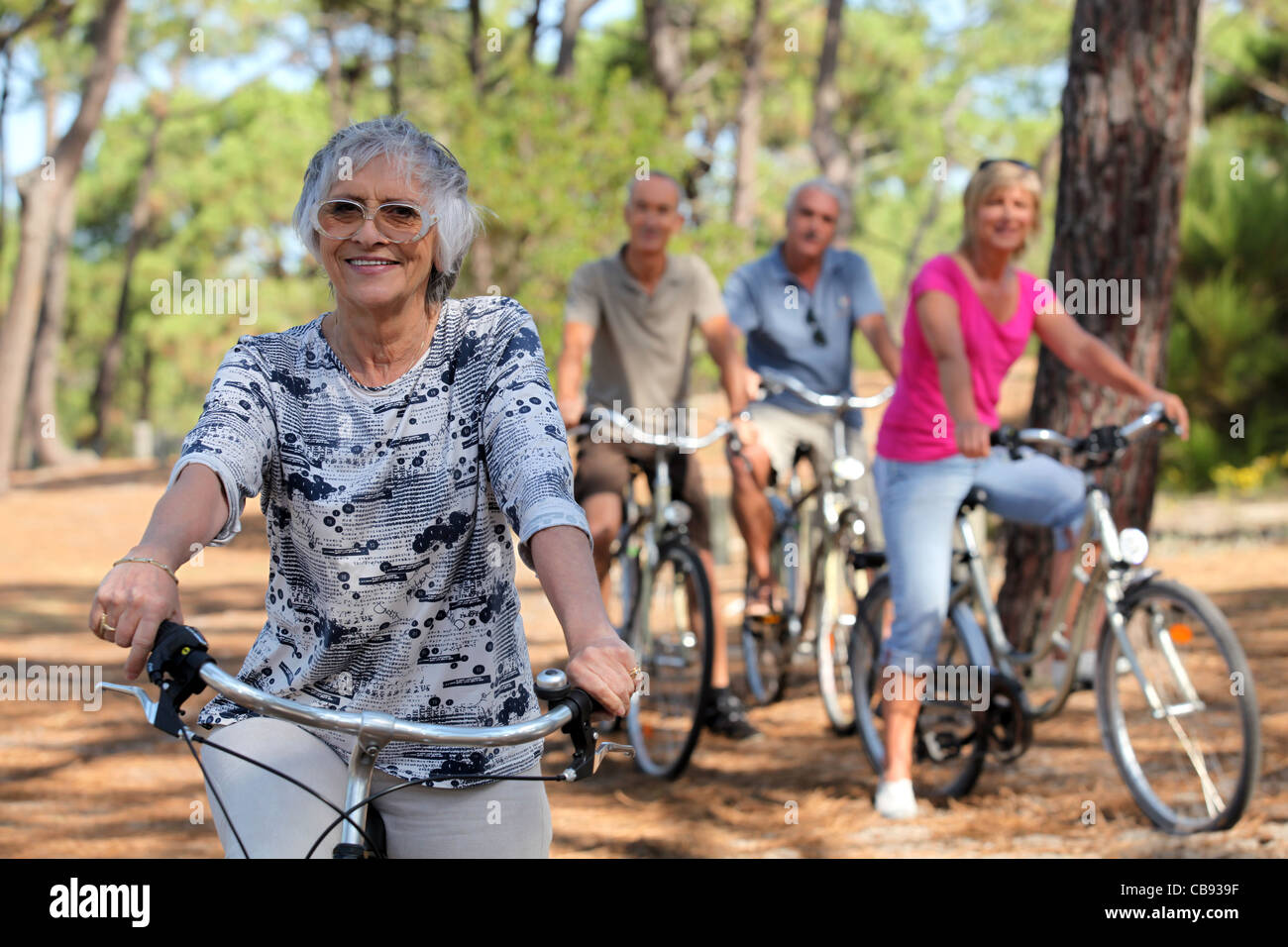 Senior Woman And Her Friends Riding Bikes Through The Countryside Senior Woman And Her Friends Riding Bikes Through The Countryside