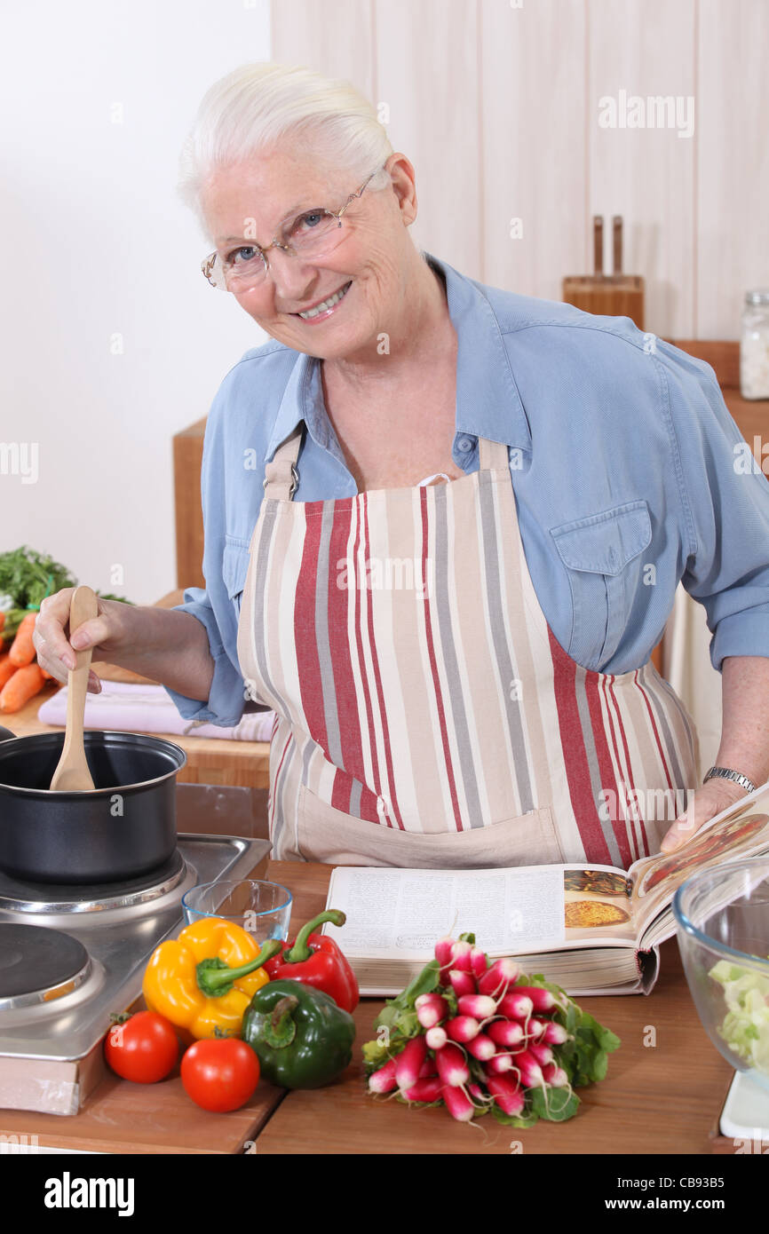 Elderly woman cooking with the help of a recipe Stock Photo - Alamy