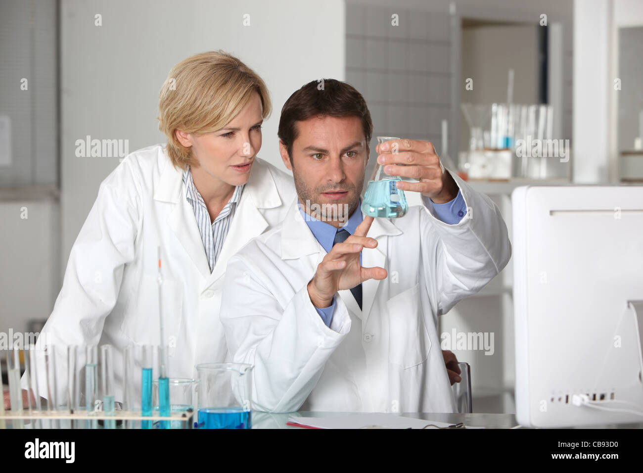 Laboratory team examining blue liquid Stock Photo - Alamy