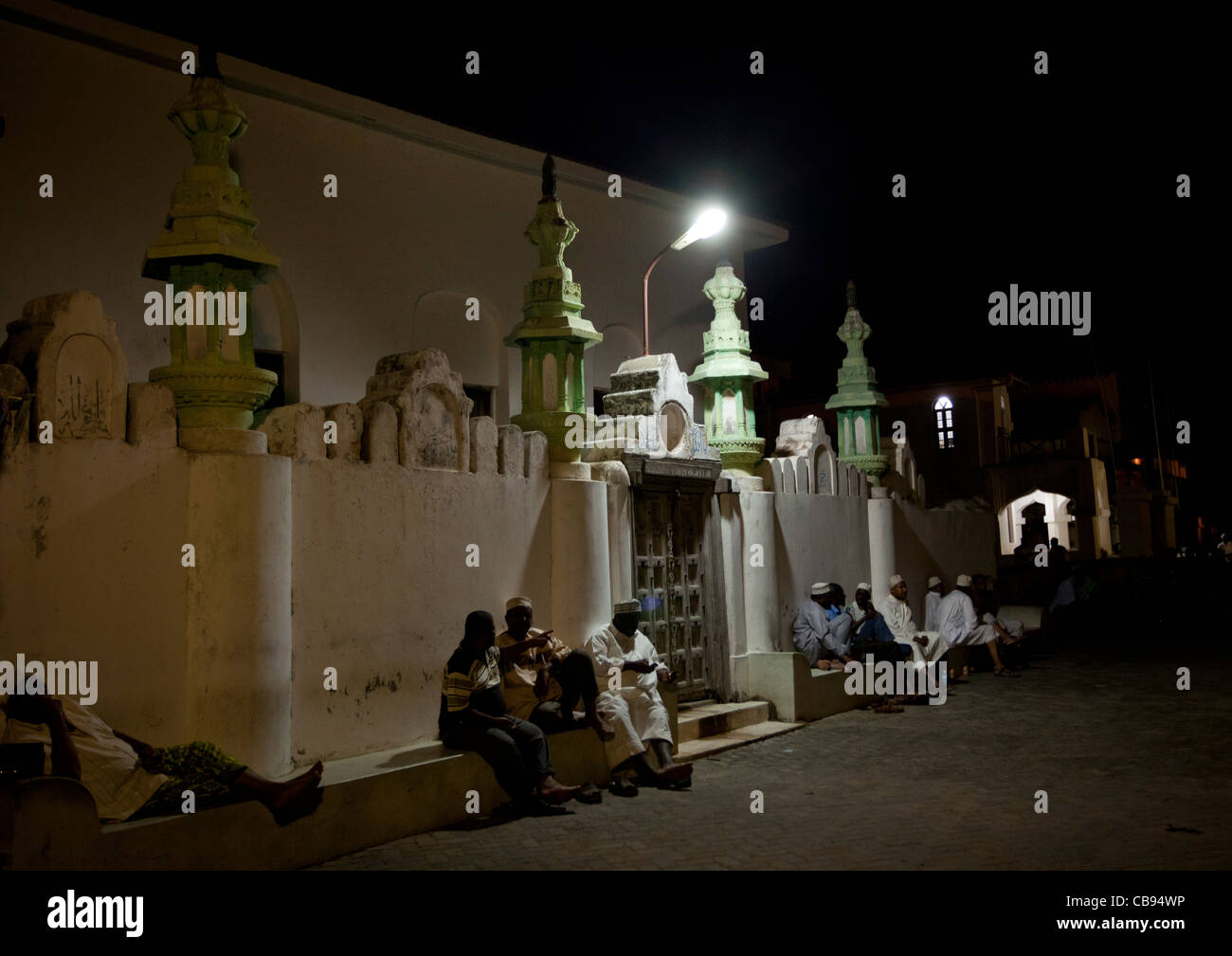 People sitting outside a house at night during Maulidi festival Stock Photo