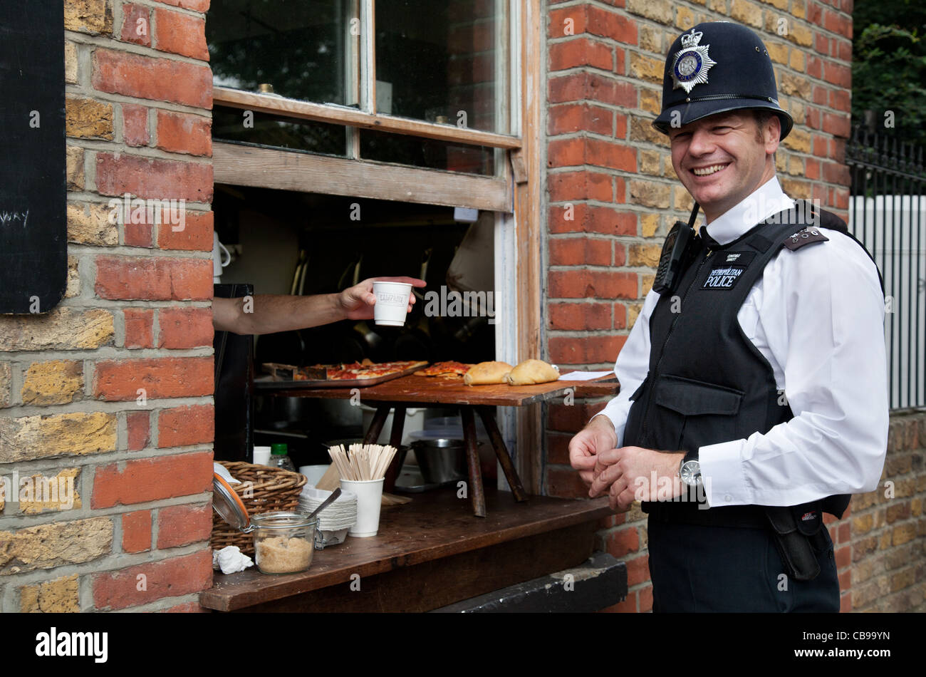 A friendly policeman 'Bobby' at lunchtime, Columbia Market, London, UK Stock Photo