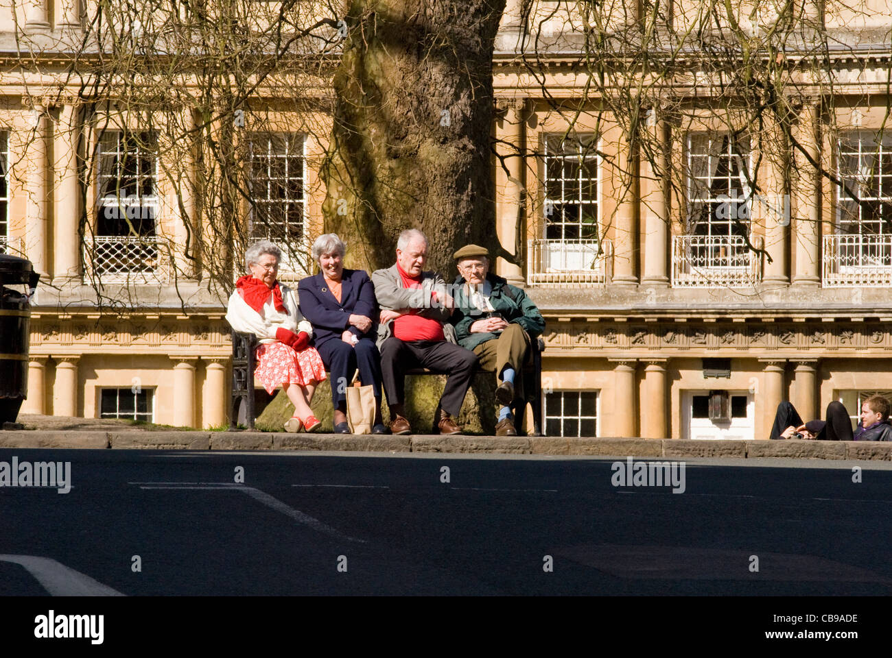 Two ladies and two gentlemen sitting on a park bench in city centre Bath, England, UK Stock Photo