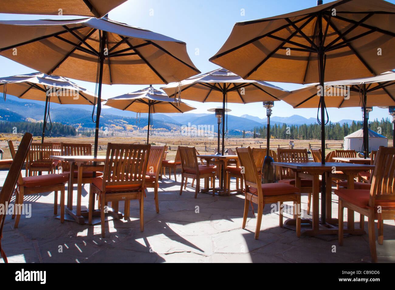 Umbrellas over outdoor patio dining area at a mountain resort lodge with scenic view of mountain range in Colorado Stock Photo