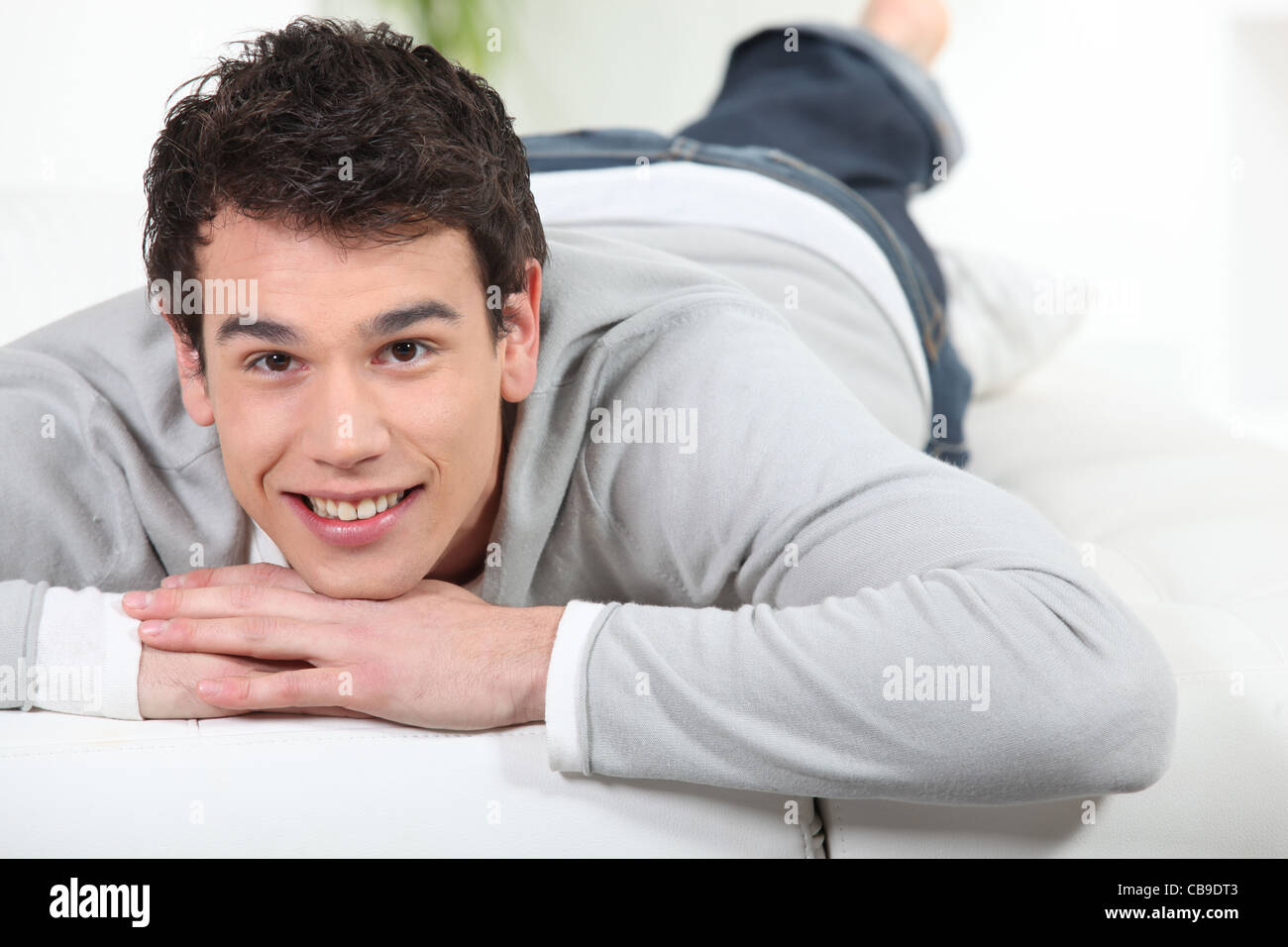 Young man lying on a sofa Stock Photo - Alamy