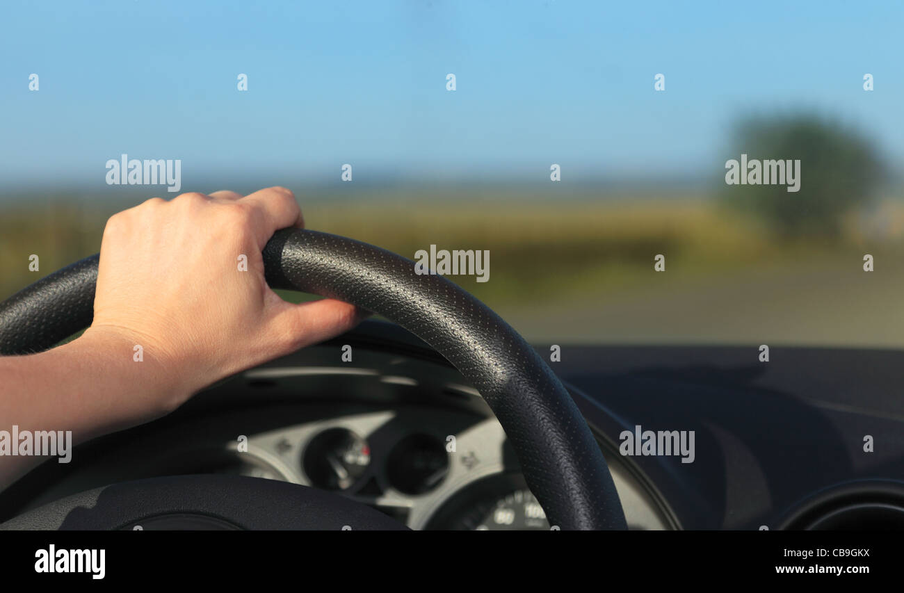 Image of the left hand of a driver holding the steering wheel Stock