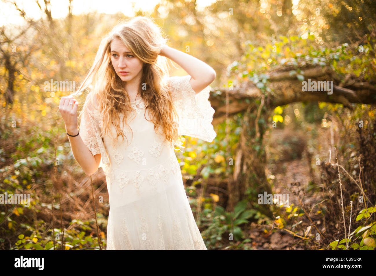 a slim blonde woman girl alone in woodland autumn afternoon daytime UK Stock Photo