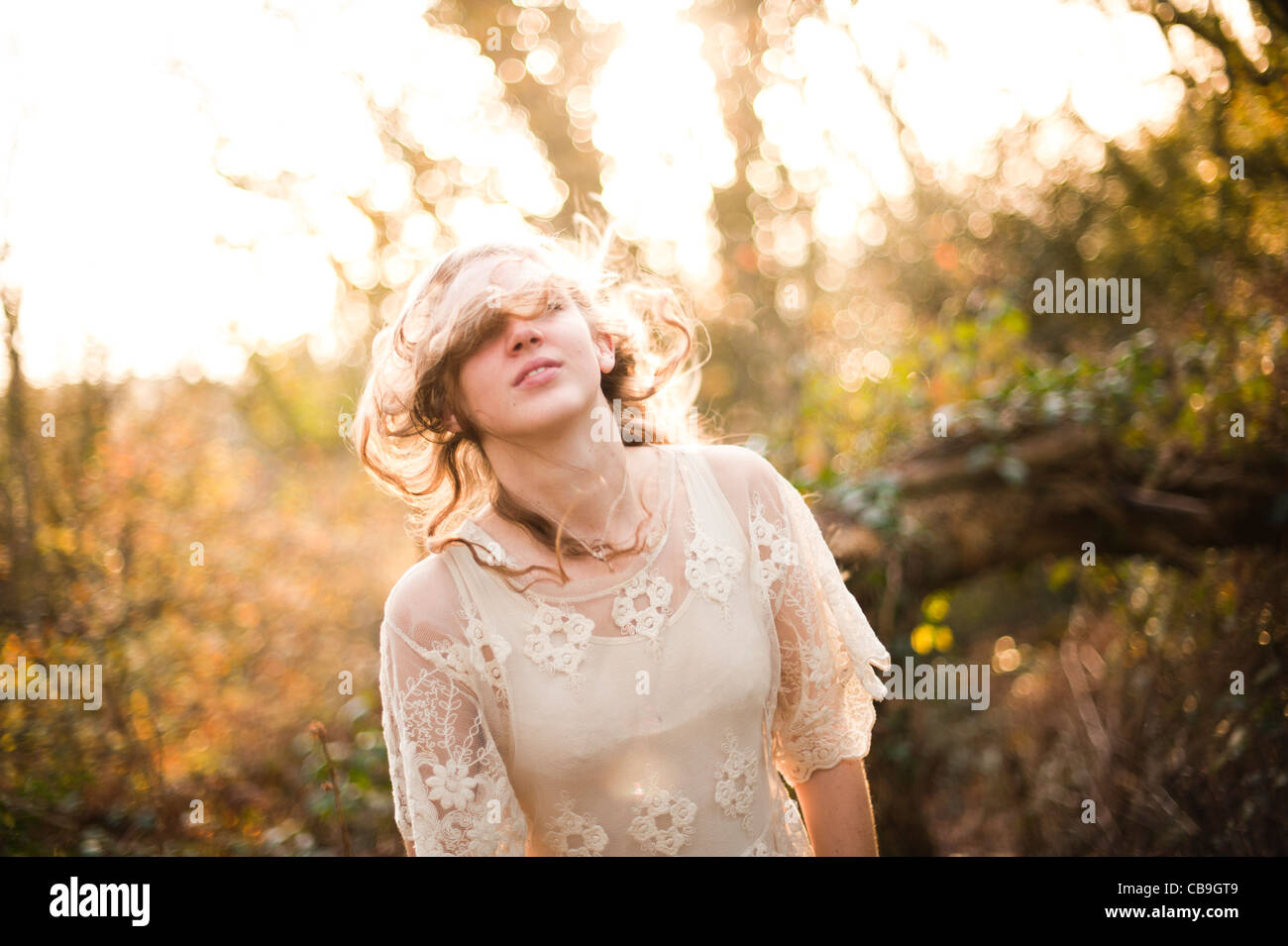 a slim blonde haired woman girl alone in woodland autumn afternoon daytime UK, backlight, backlit Stock Photo