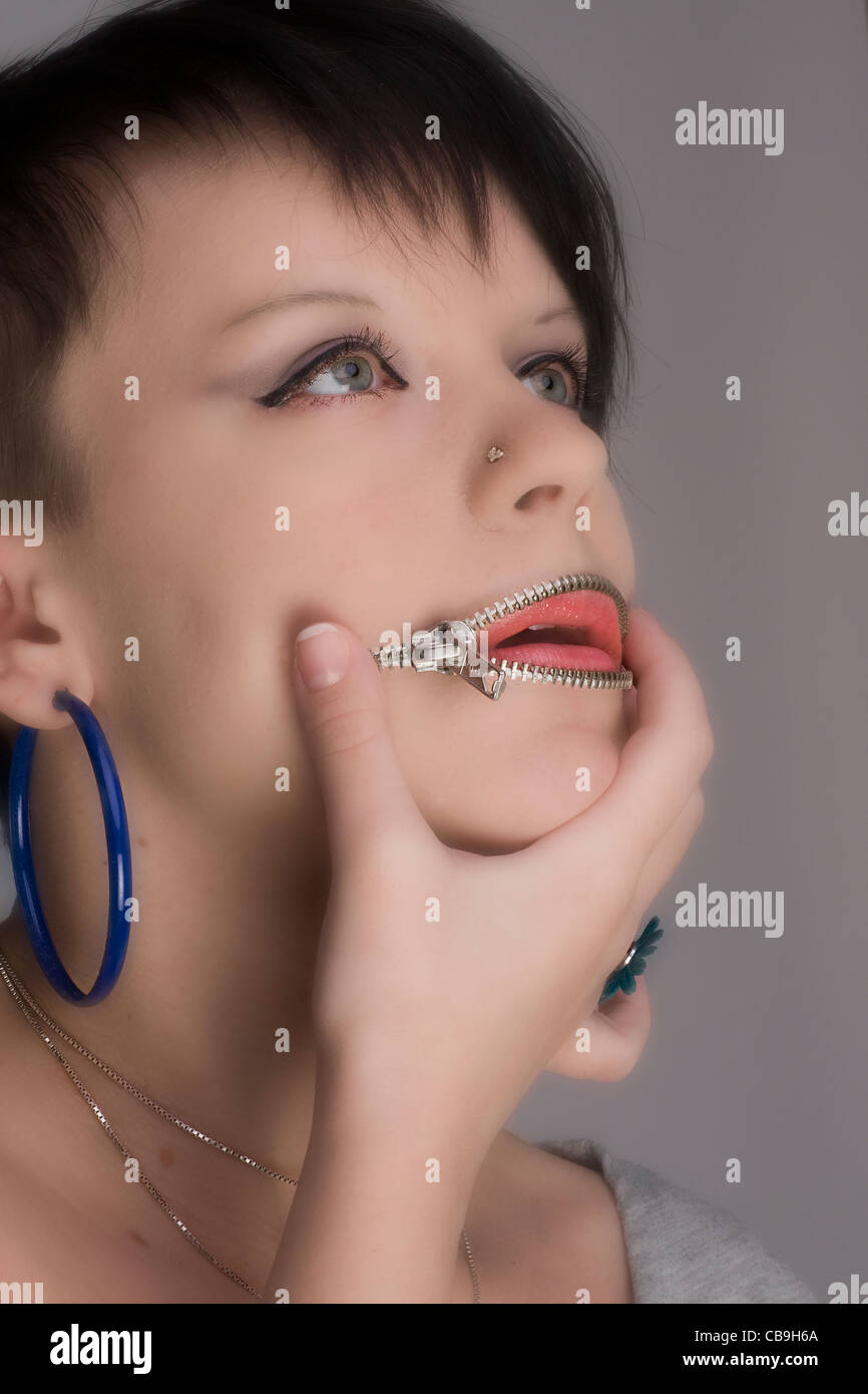 A beauty young woman having the mouth equipped with the zipper. A humorous photo. Stock Photo