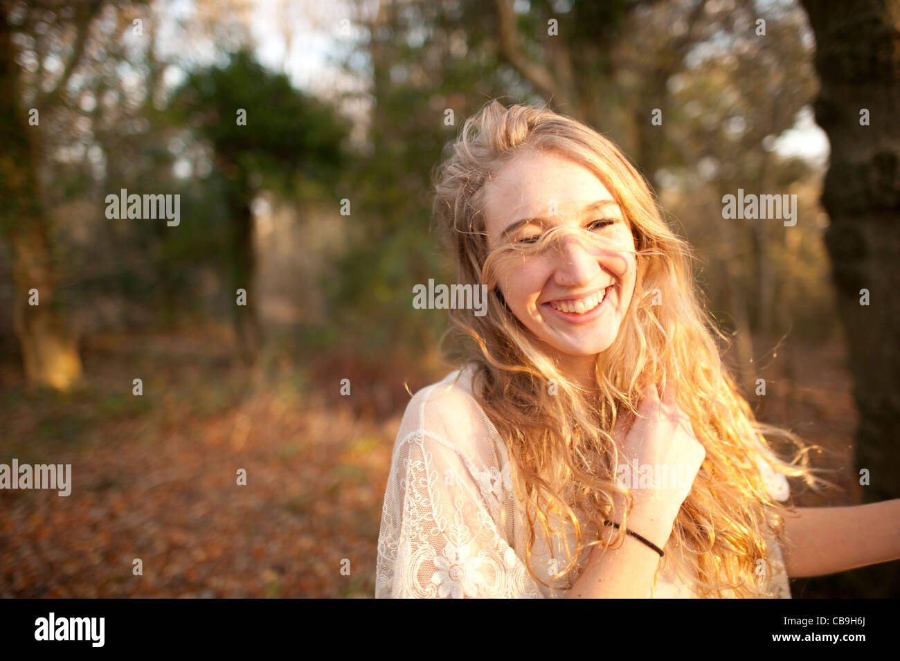 a happy smiling slim blonde woman girl alone in woodland autumn afternoon daytime UK Stock Photo