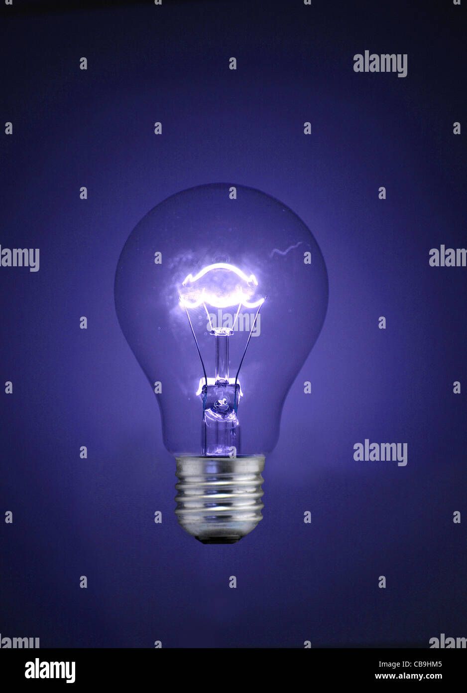 A traditional tungsten, screw-fit  light bulb. Illuminated - though not visibly connected to an electrical supply. Stock Photo