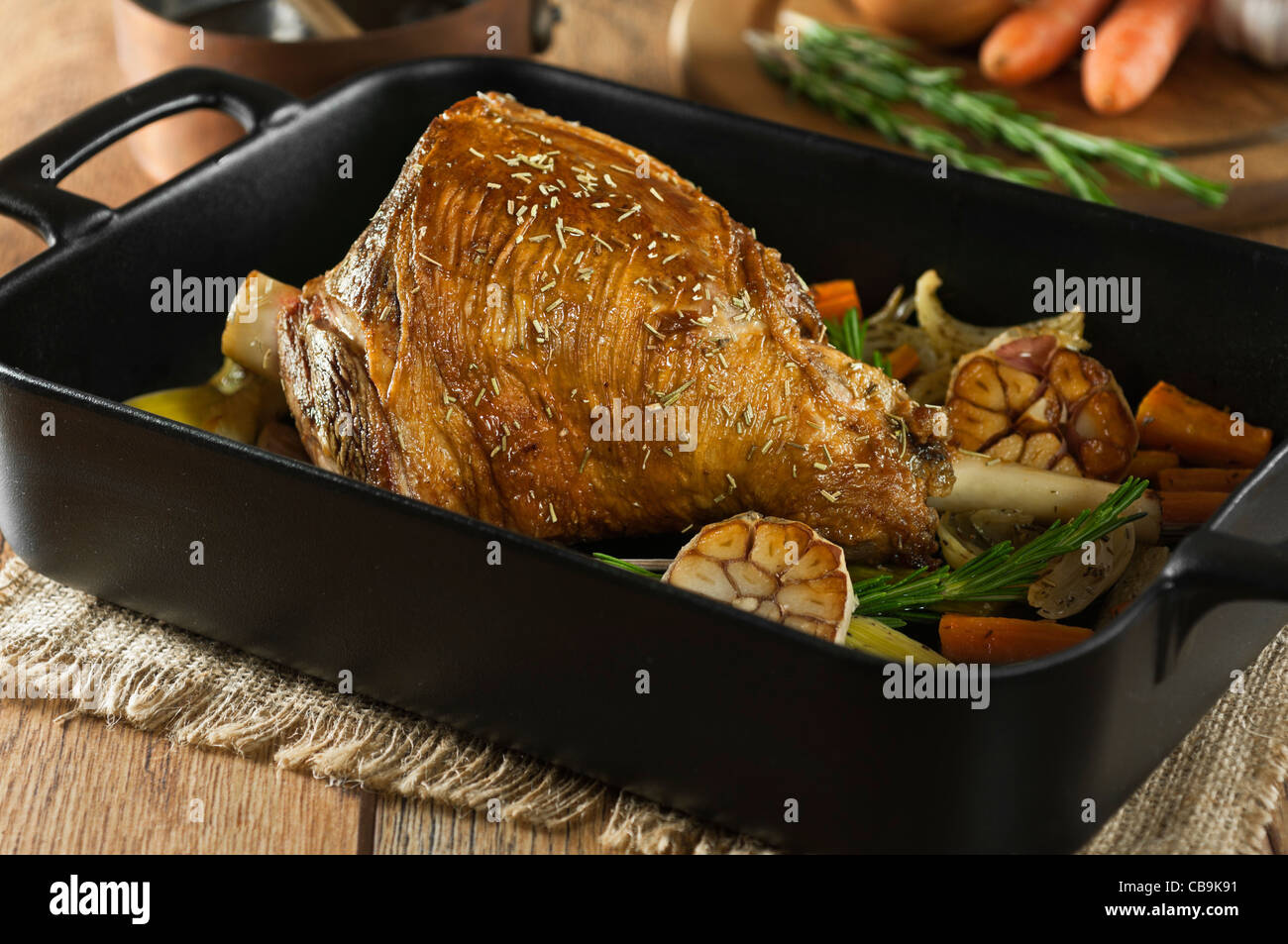 Roast leg of lamb with garlic and rosemary in a roasting tray Stock Photo