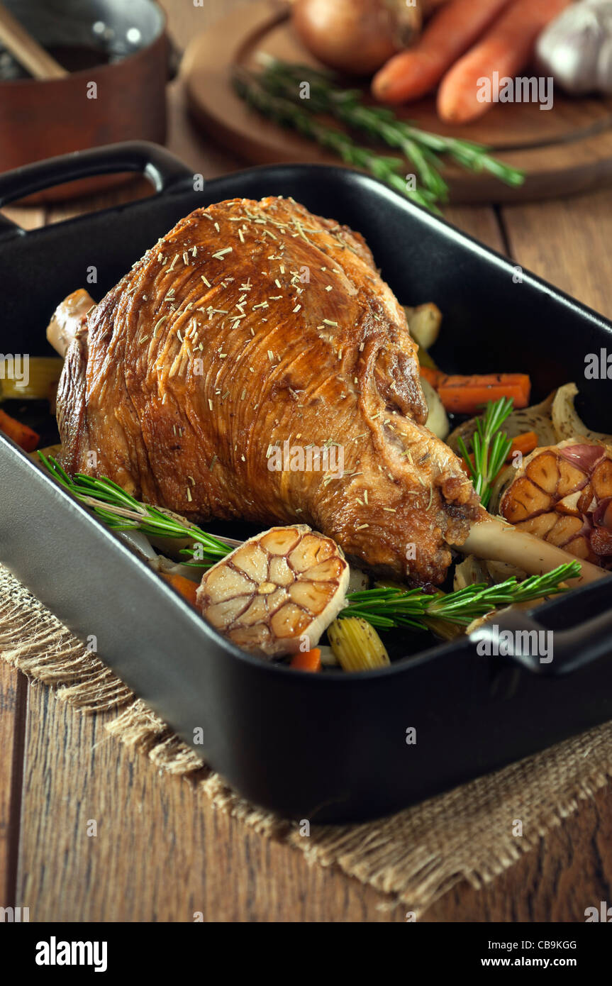 Roast leg of lamb with garlic and rosemary in a roasting tray Stock Photo