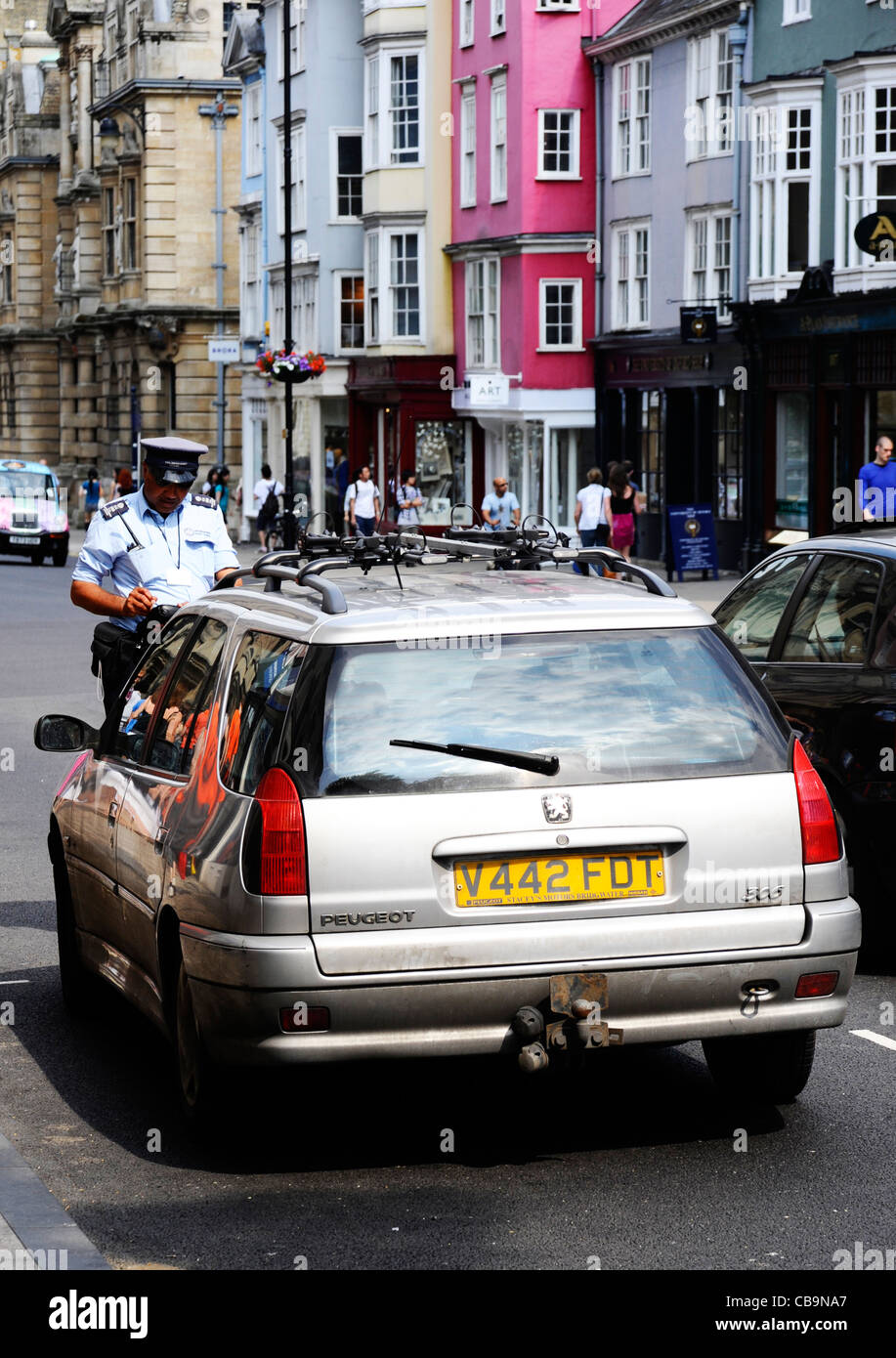 A traffic warden writing out a parking ticket in Oxford, UK Stock Photo
