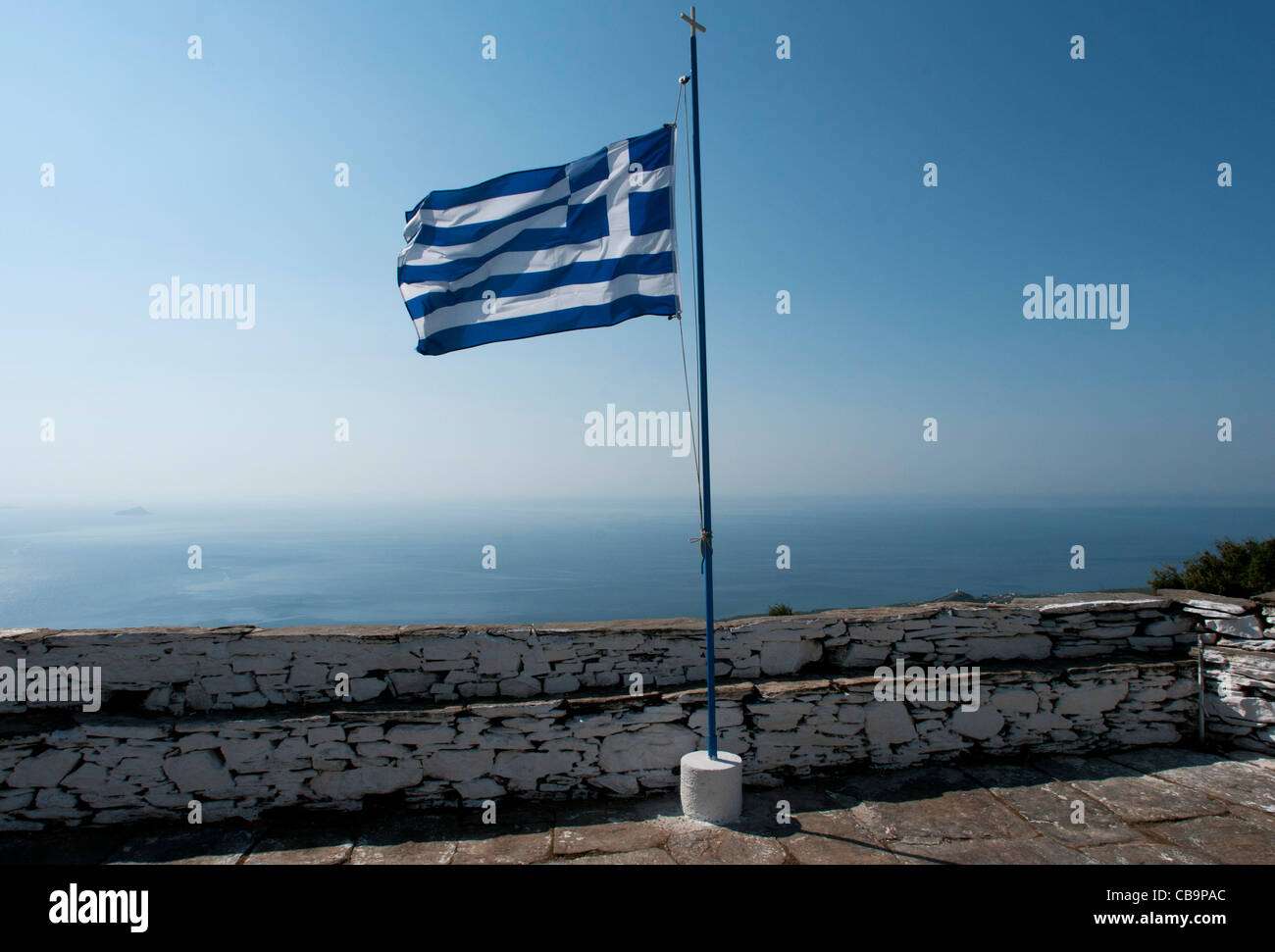 Greek flag flying over the Aegean sea, Ikaria island, Greece Stock Photo