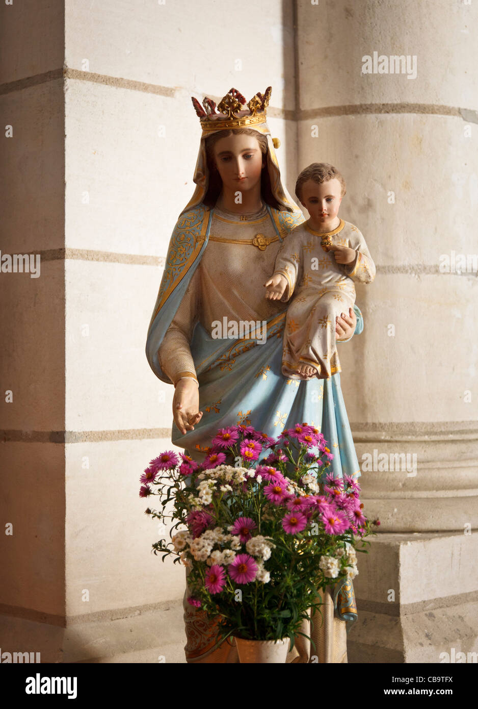 Virgin Mary and Jesus statue in a church with flowers in front Stock Photo