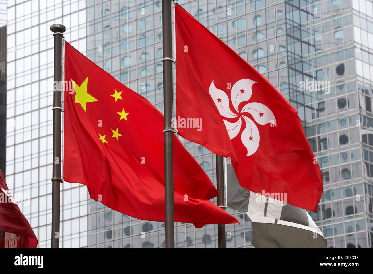 chinese and hong kong flags flying with office buildings behind hong kong hksar china Stock Photo