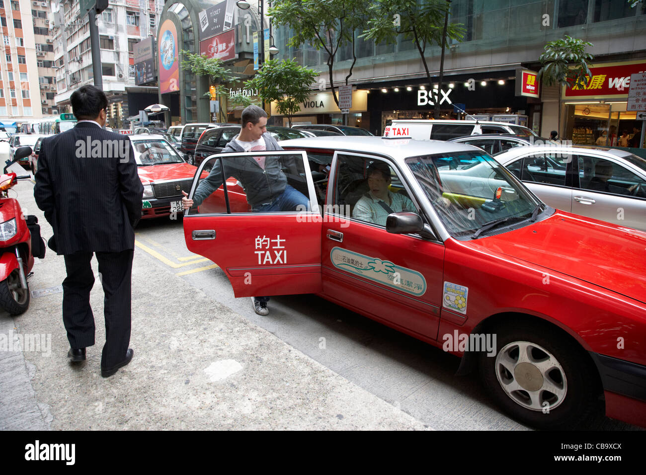 western tourist getting into a cab in the front of a row of hong kong red cabs downtown taxi rank hong kong island hksar china Stock Photo